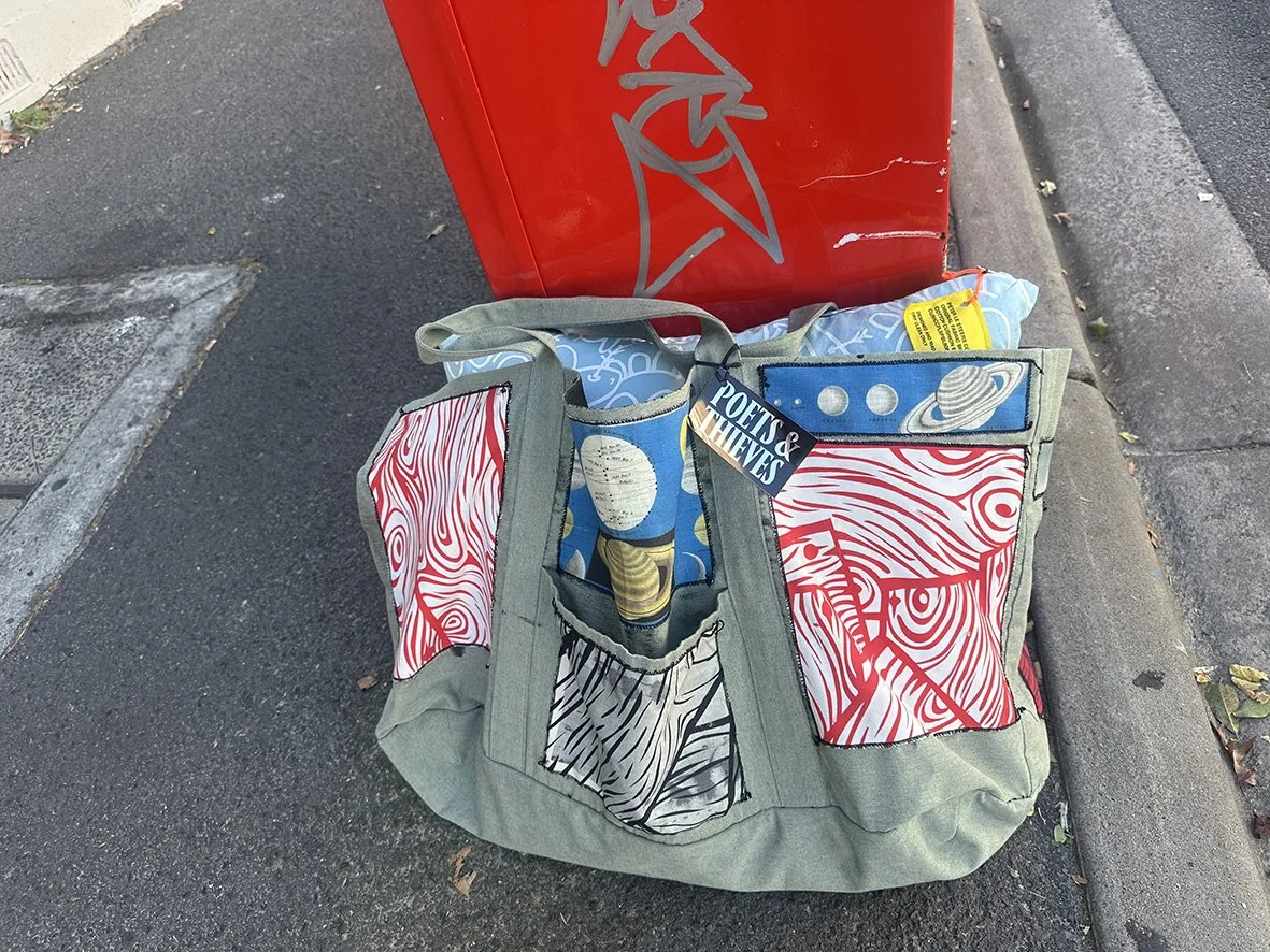 Canvas sage oversized bag with astrology and woodgrain patches, resting against a post box.