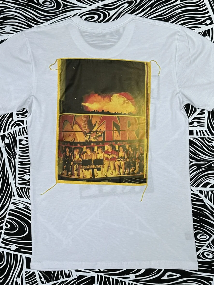 Back view of white tee with a large yellow patch featuring Big Day Out images by Sophie Howarth.
