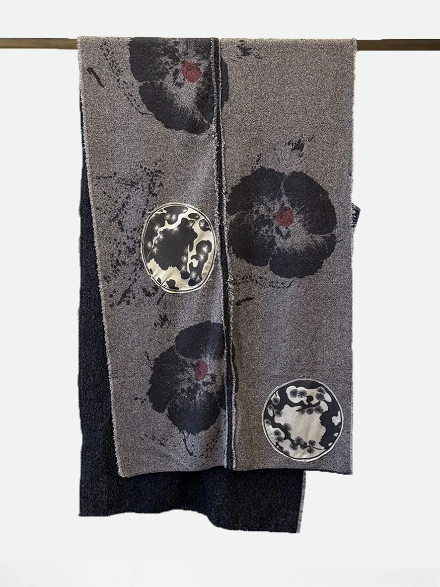 An image of the back of a long slim wool blend and silk throw with frayed edging in black poppies and cream silk Japanese flowers.