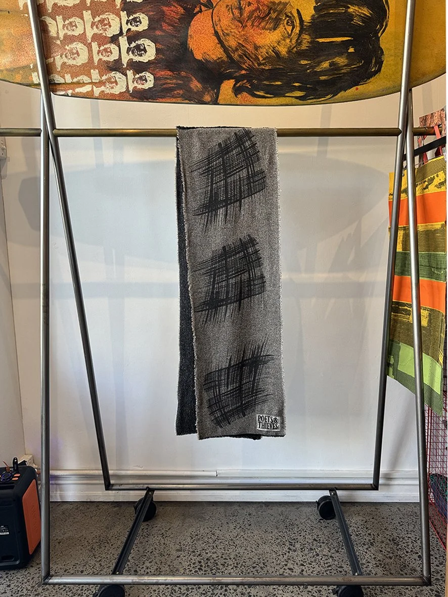 Flymo slim wool scarf with graphic by Andrea Prosciutti hung on a rack in the Hoponit store with a Bromley surfboard.