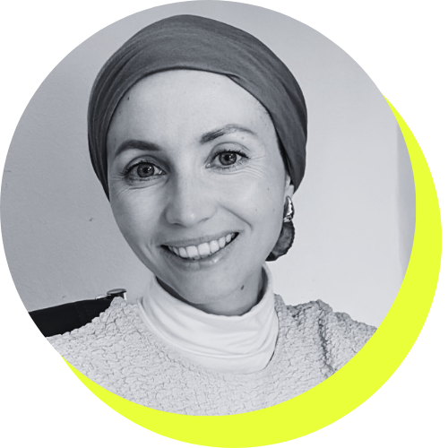 Black and white portrait of a smiling woman wearing a headscarf and earrings, with a light-colored top.