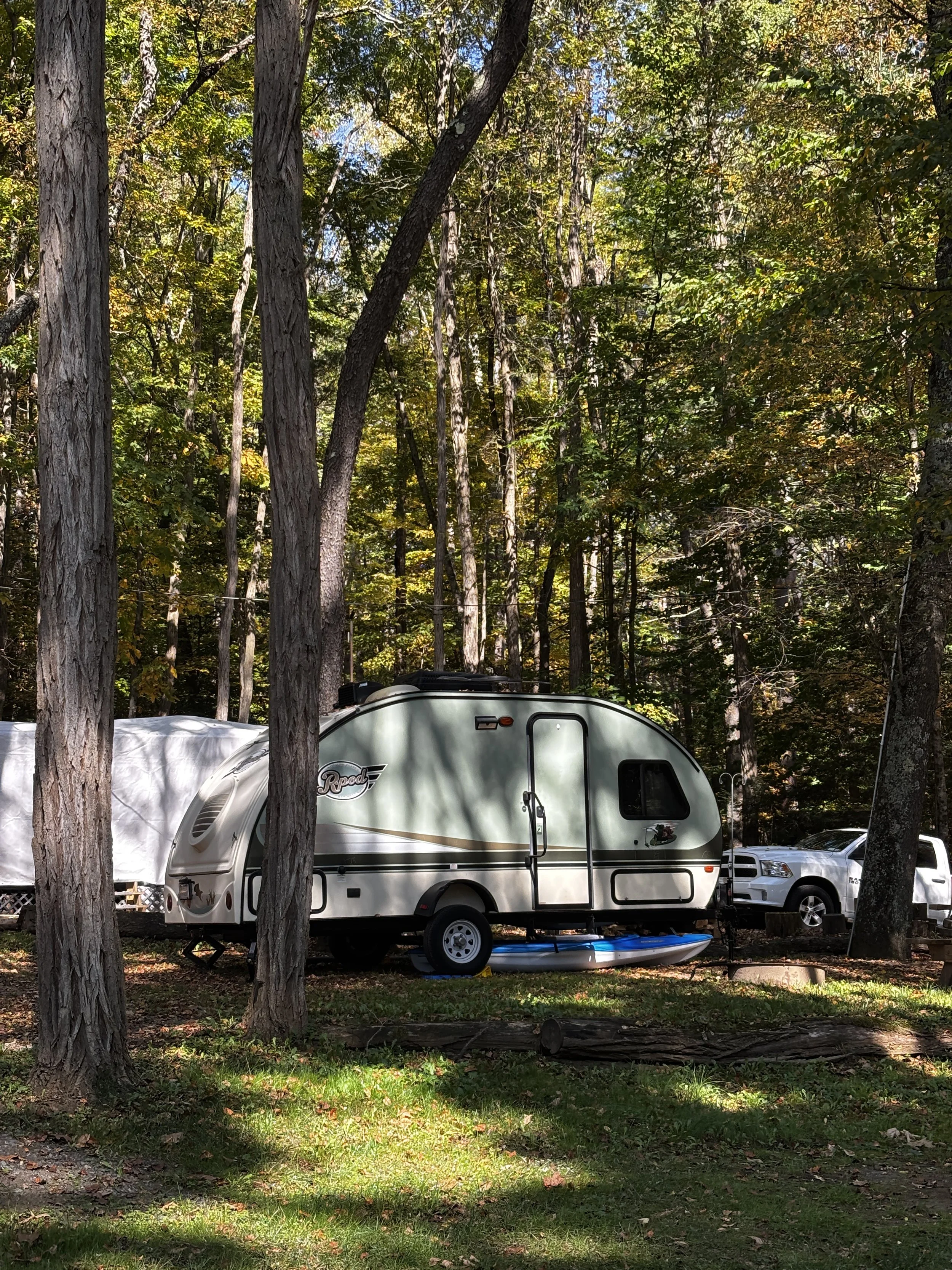 A teardrop travel trailer is parked among trees in the forested Adirondacks near Lake George and Saratoga Springs.