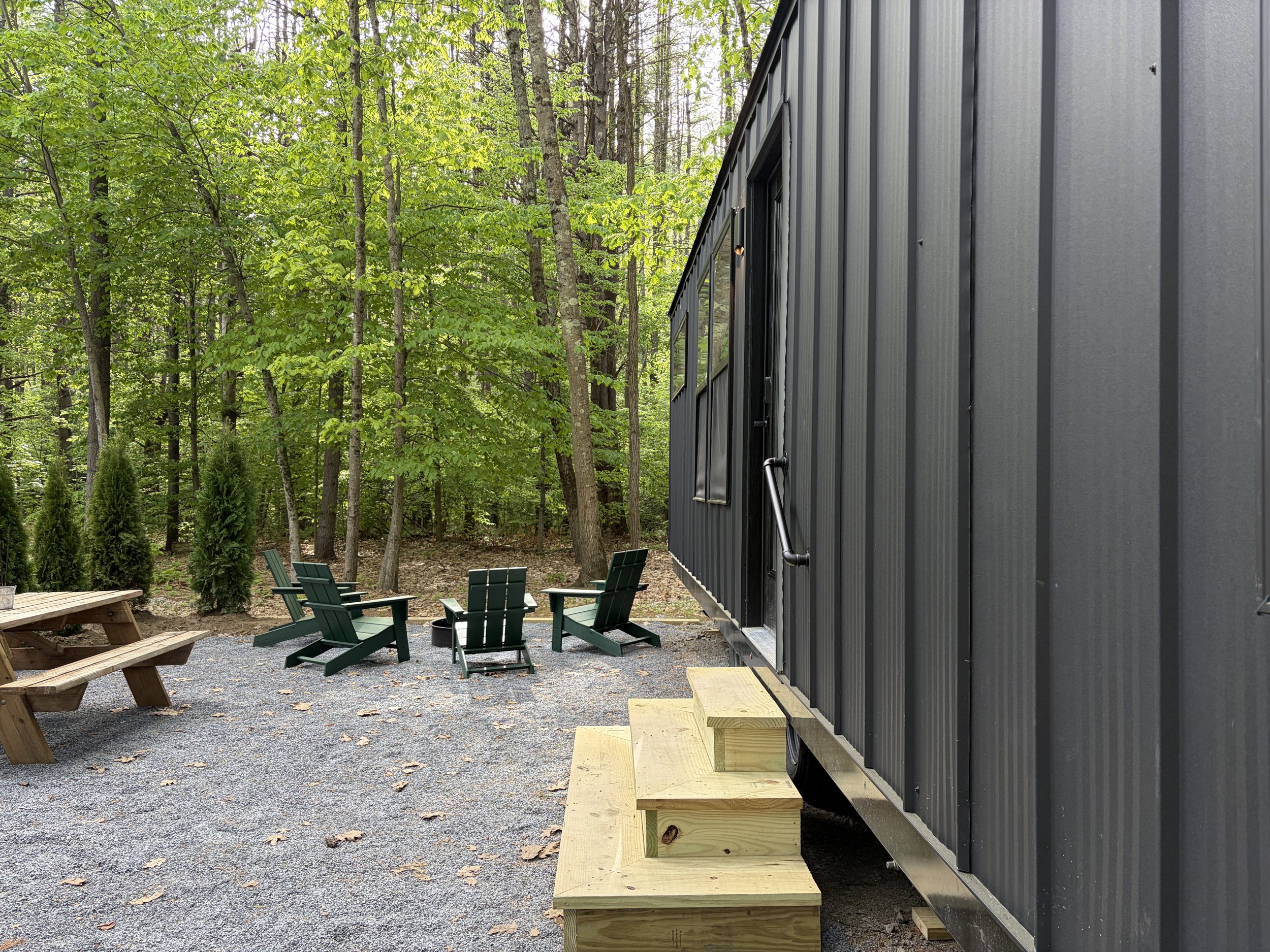 The Walnut looks out on to the forest and has a setup with picnic tables, Adirondack chairs, a firepit and a Blackstone grill.