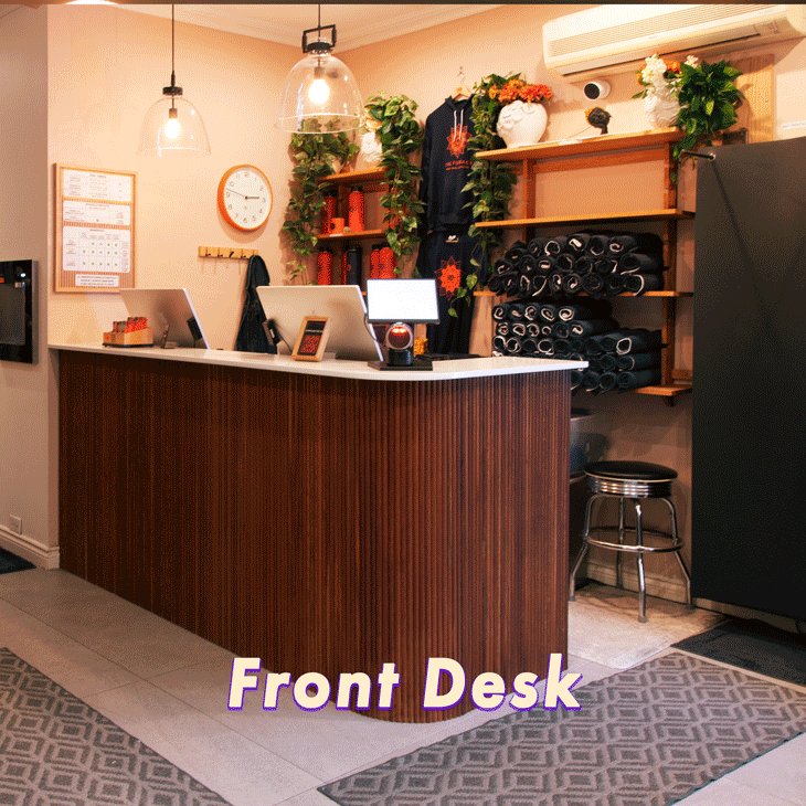 Group of people participating in a yoga class in a mirrored studio, stretching with one arm raised and bending sideways on yoga mats.