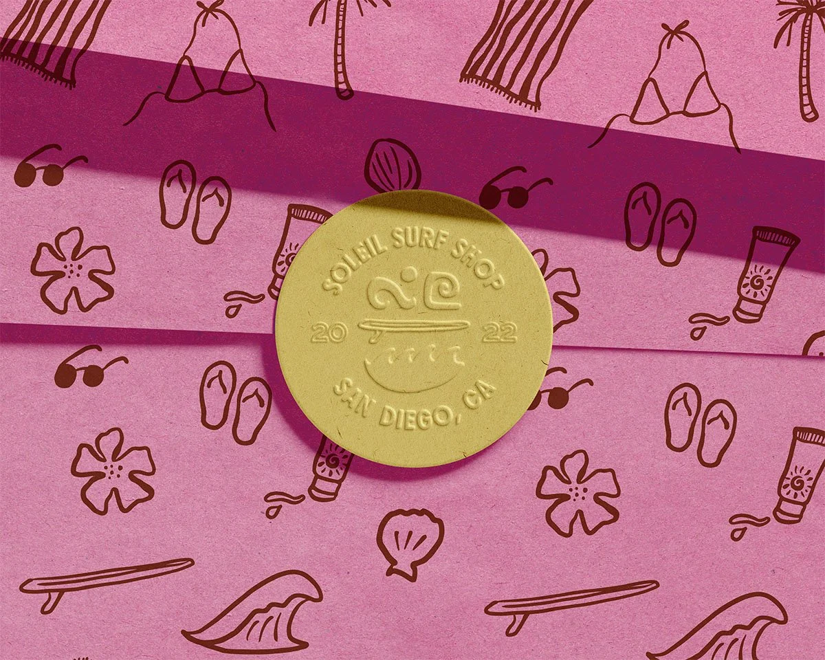 San Diego Surf Shop branding emblem placed on custom paper with beach-related illustrations, including flip-flops, sunglasses, a flower, a shell, a surfboard, sunscreen, and a bikini.