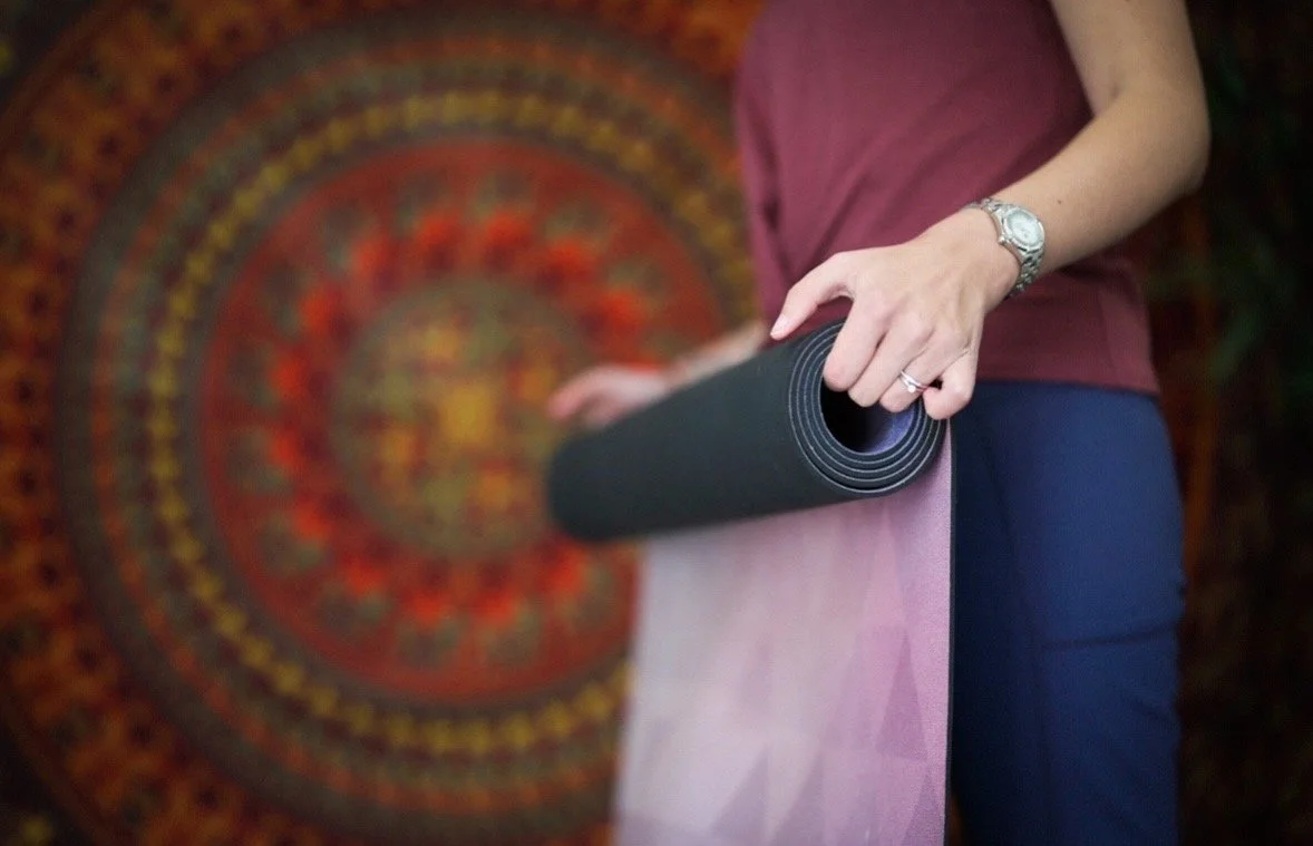 Sam holding a rolled yoga mat at The Wellness Hut