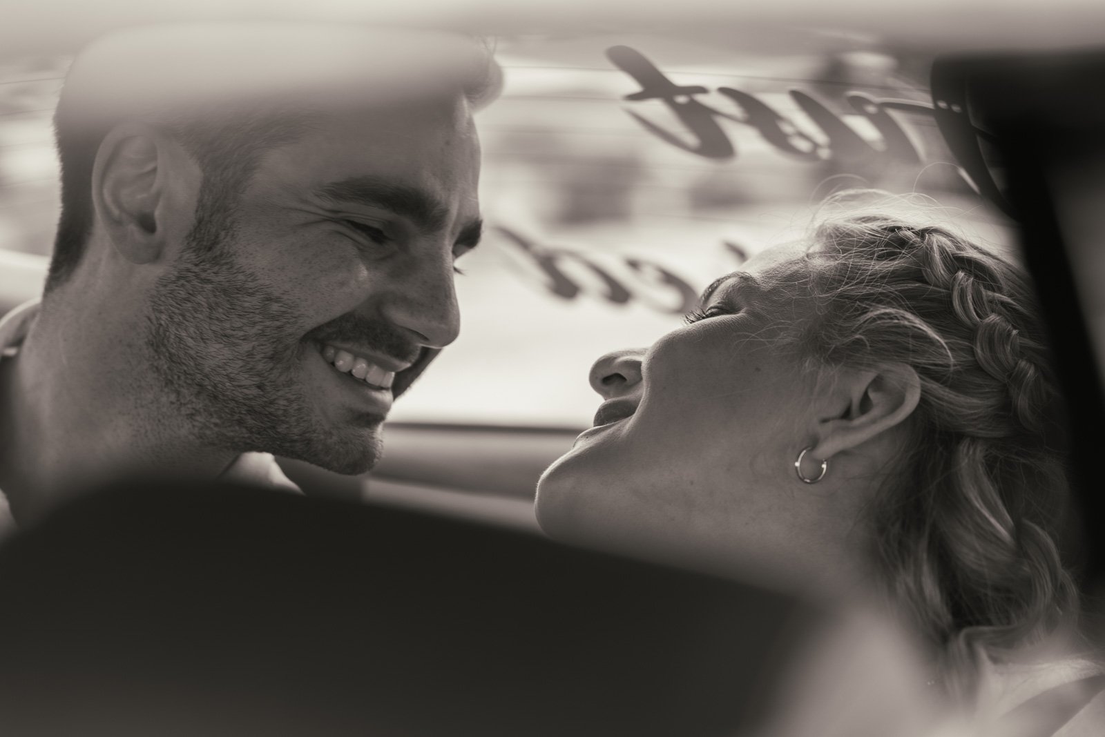 Ein Mann und eine Frau lachen und schauen sich liebevoll an, während sie in einem Auto sitzen.