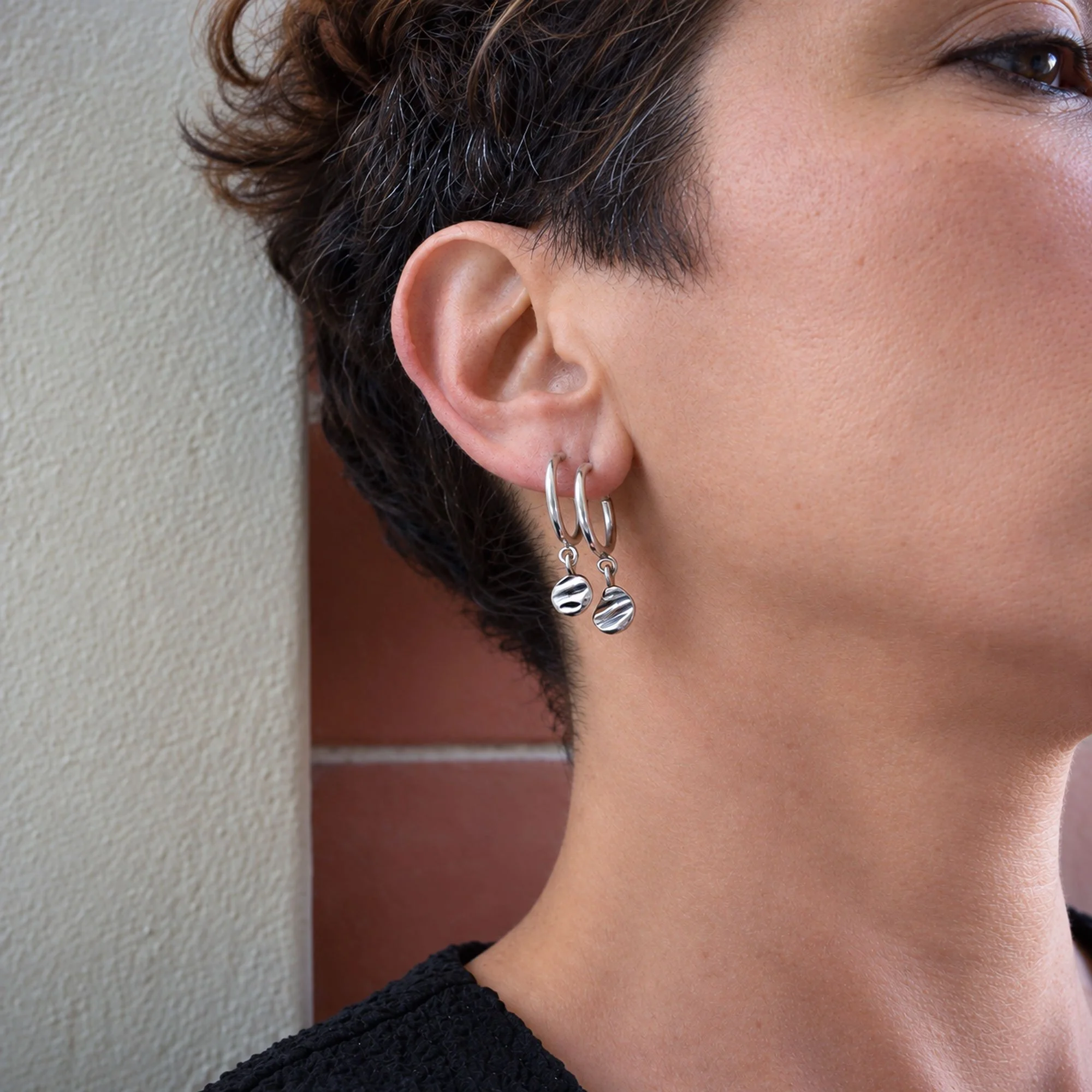 Minimalist stackable hoop earrings with textured shell charms, handmade recycled silver jewelry with an organic coastal design.