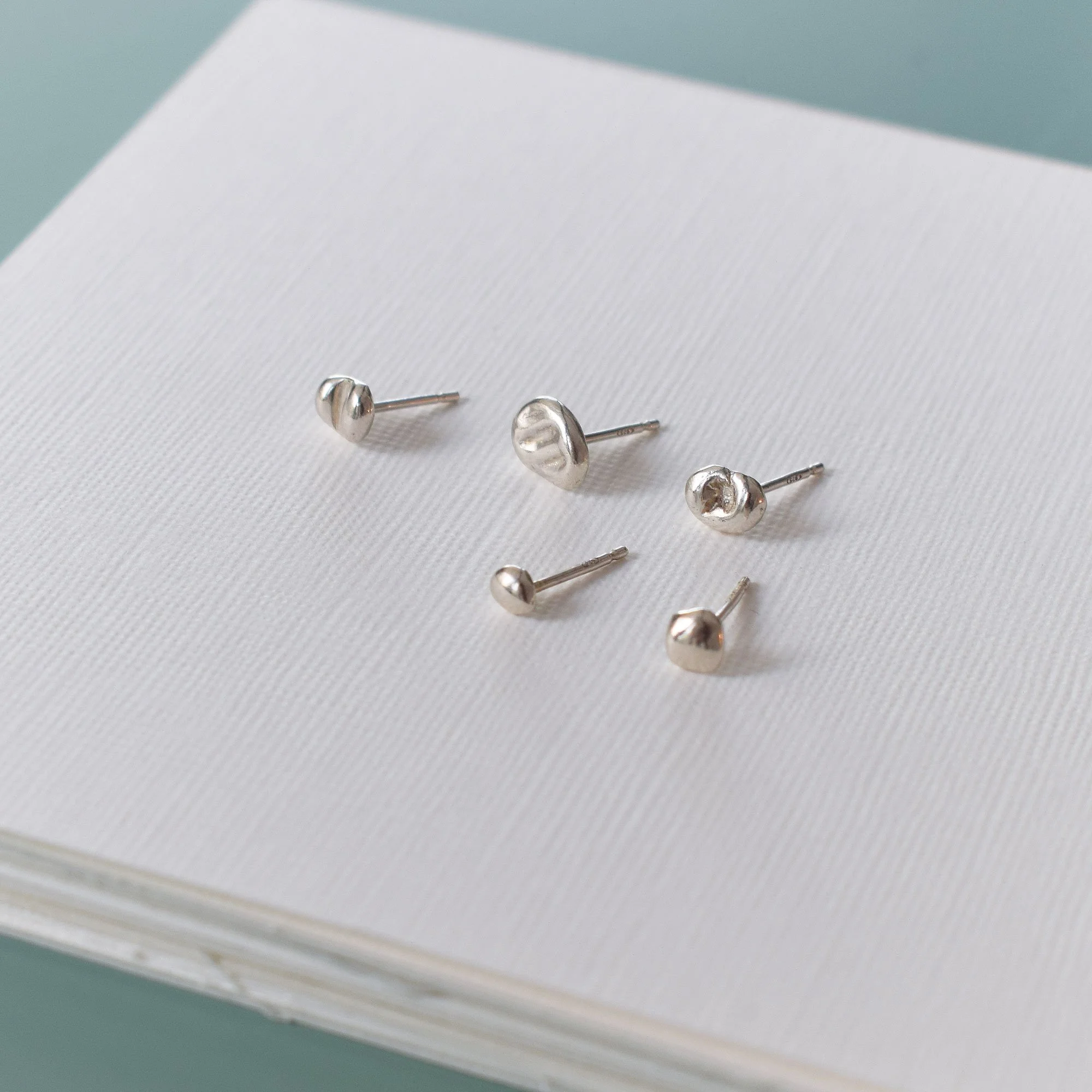 A set of irregular, mismatched stud stackable earrings with a liquid silver look and unique texture. Handmade from recycled sterling silver 925 by Greek jewelry brand meet the cat.