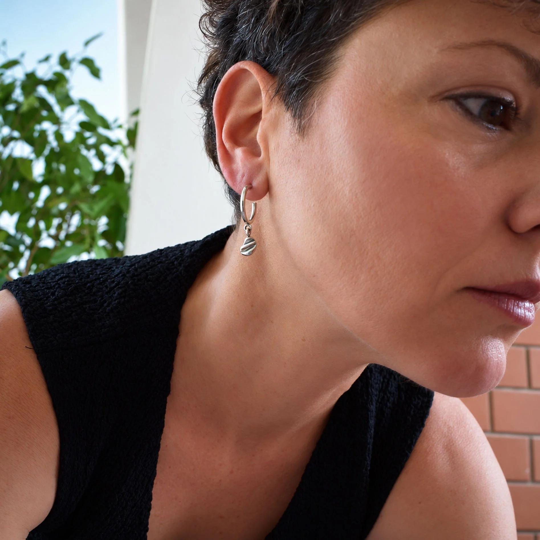 Nature-inspired sterling silver hoop earrings with handmade shell texture charms, artisan recycled silver jewelry with an organic finish.