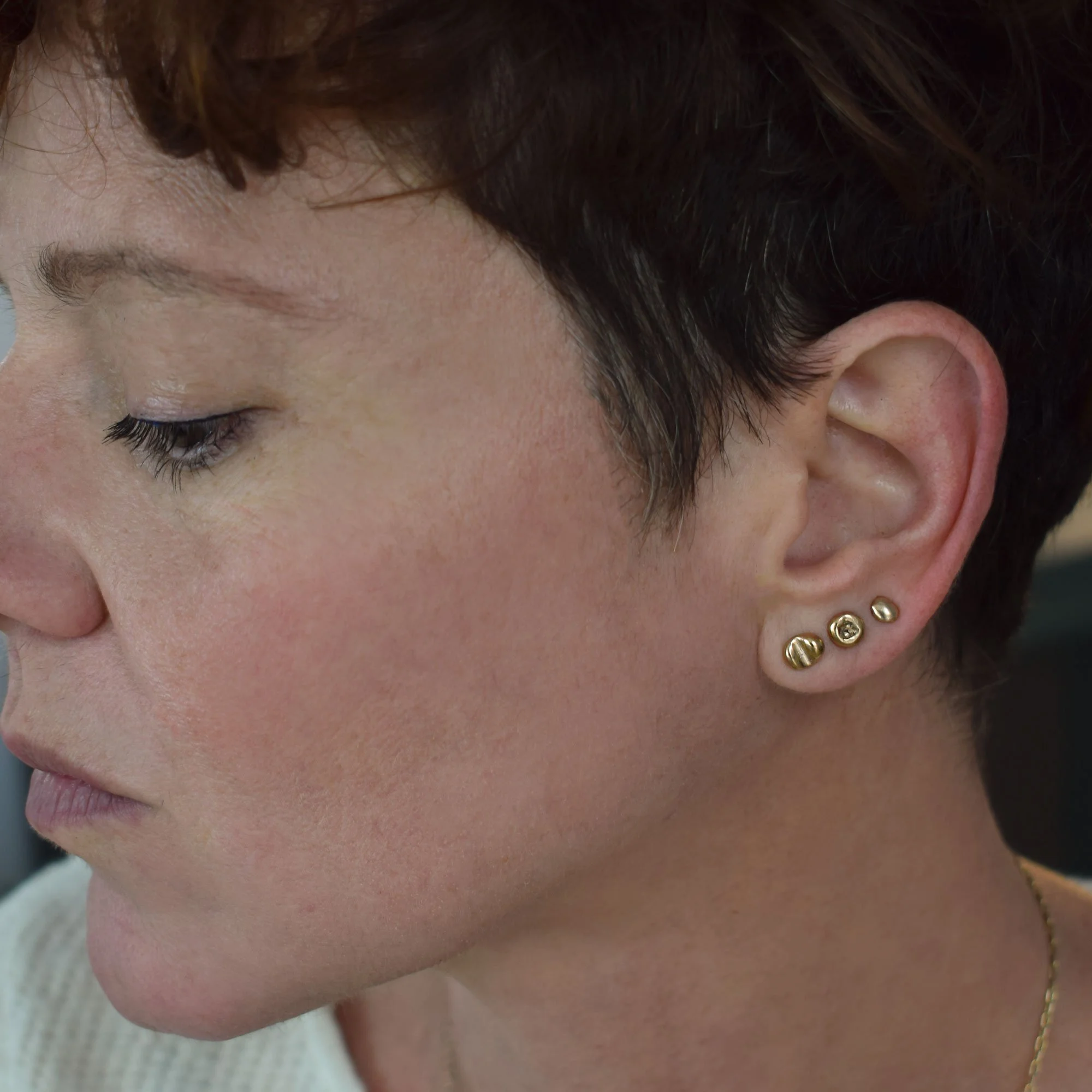 A set of irregular, mismatched stud stackable earrings with a liquid gold look and unique texture. Handmade from bronze and silver posts and fastenings by Greek jewelry brand meet the cat.