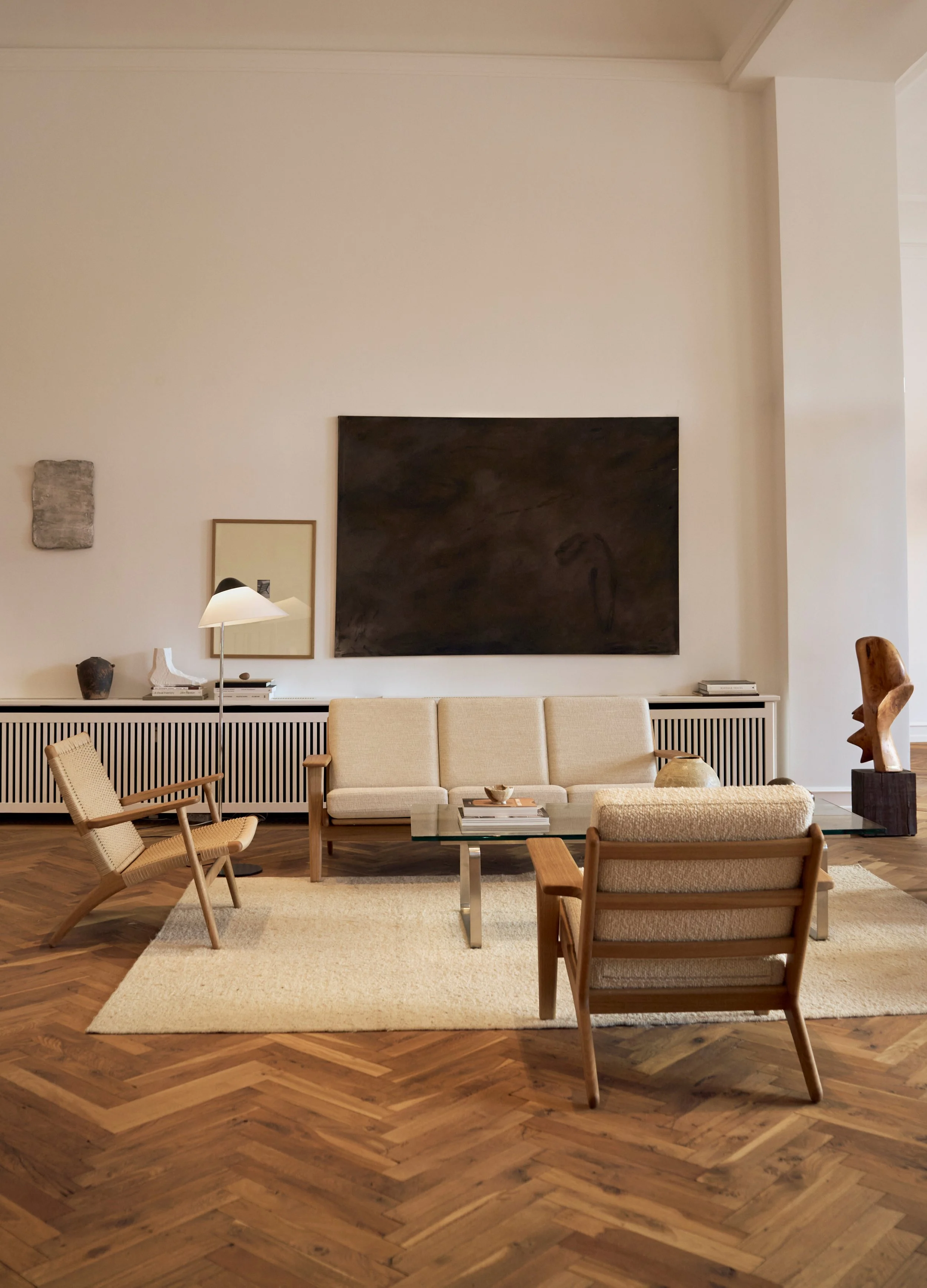 Minimalist living room at the Carl Hansen & Søn showroom in Copenhagen with a Hans J. Wegner CH293 three-seater sofa, and CH25 lounge chair, and oak herringbone flooring. 