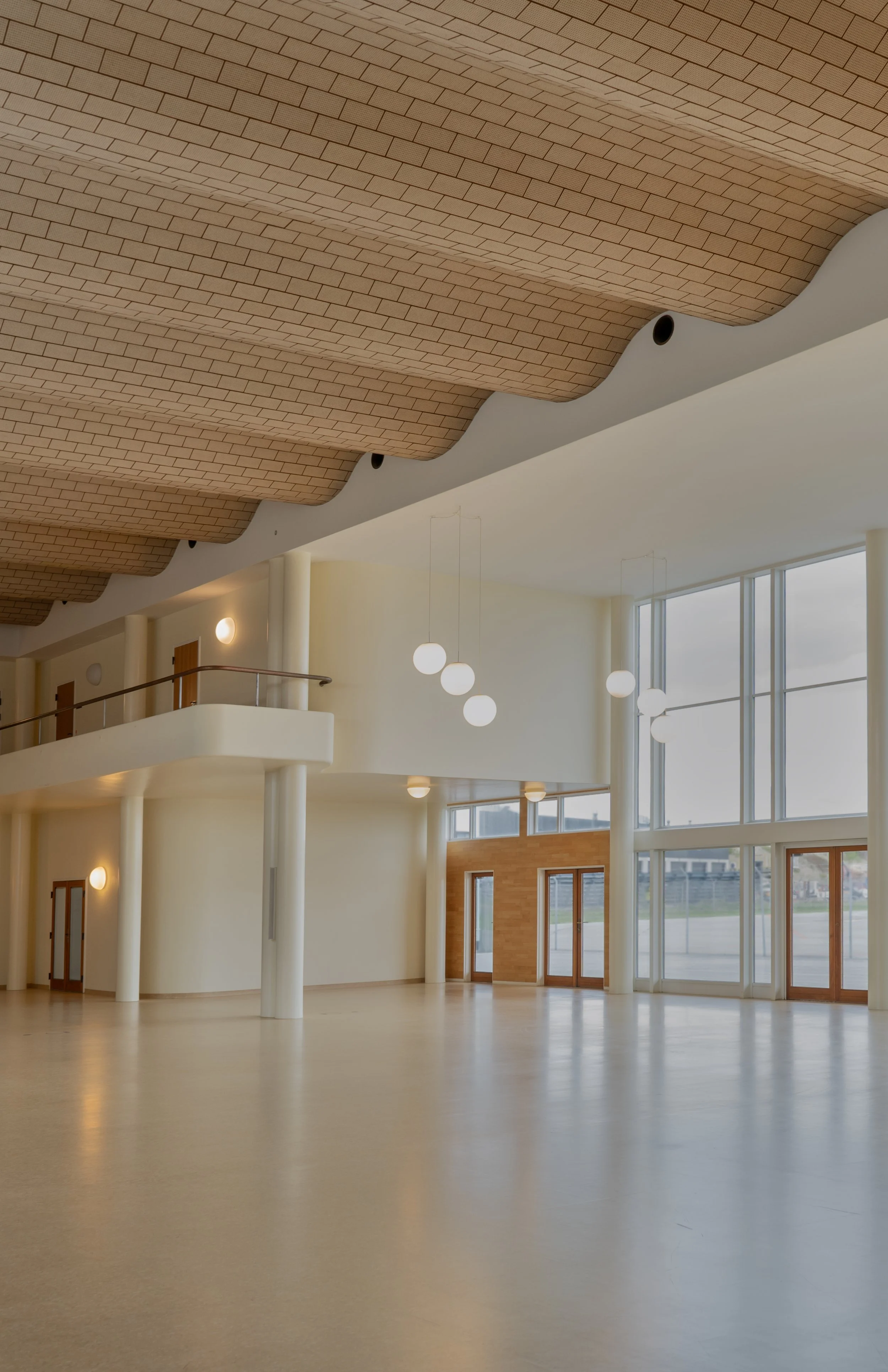 Interior architectural photograph of the Vilhelm Lauritzen Terminal, showcasing a prime example of Danish Functionalism. The frame captures the signature undulating, sound absorbing brick ceiling and expansive open terminal hall, using soft ambient l