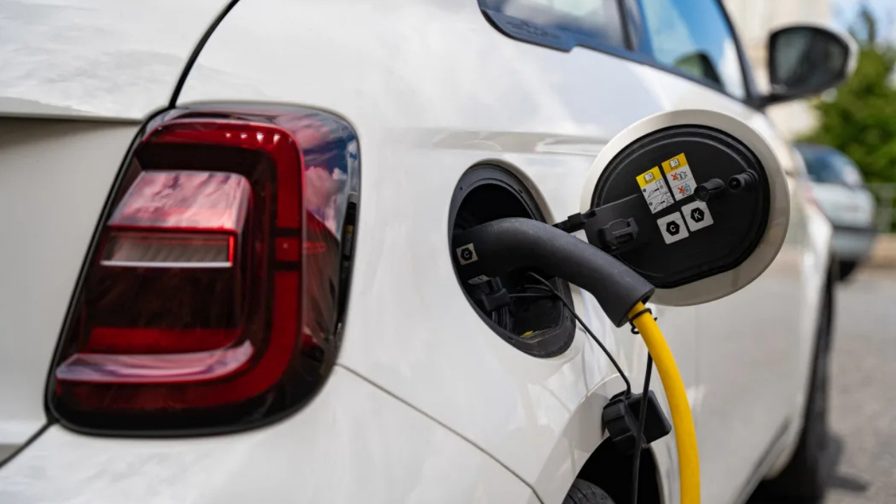 Close-up of a white Fiat 500e plugged into a charging station, showcasing the simplicity of EV charging.
