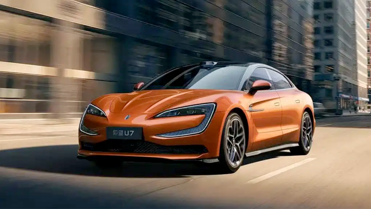 Orange Yangwang U7 luxury sedan driving on a city street with distinctive C-shaped headlights and roof-mounted LiDAR.