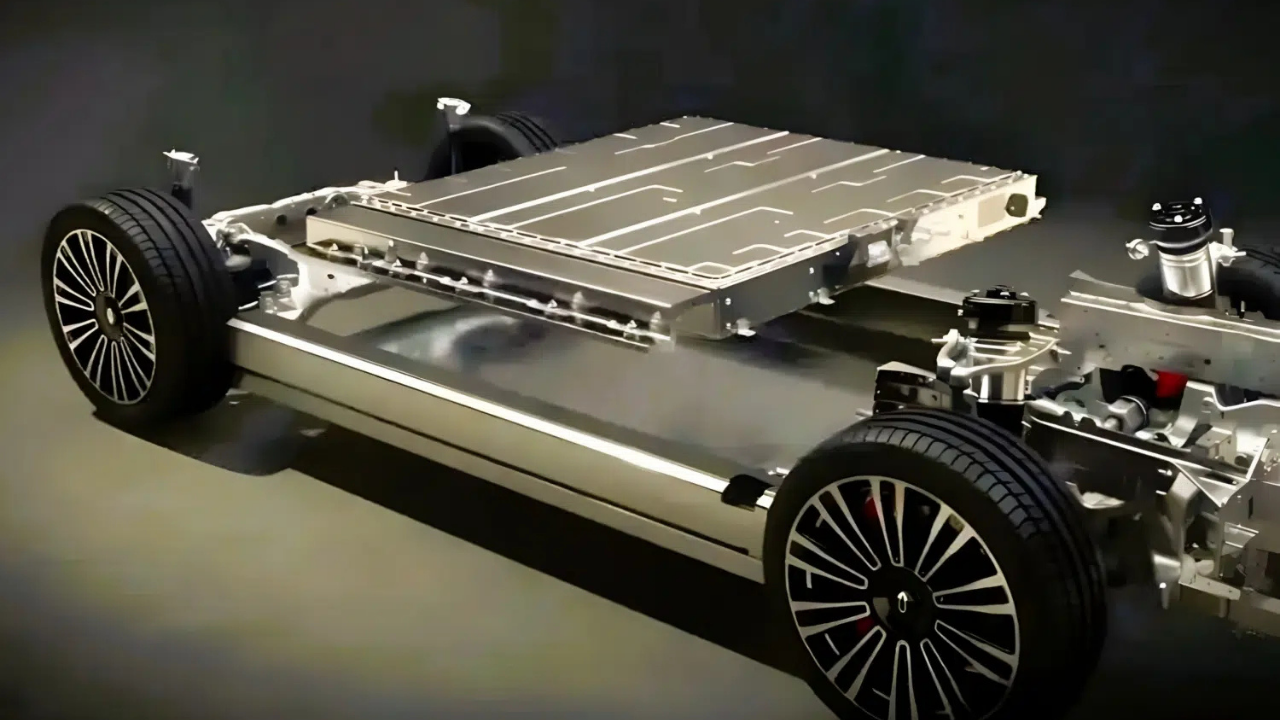 Rendering of a silver BYD EV skateboard chassis with a large flat battery pack and multi-spoke wheels on a dark background.