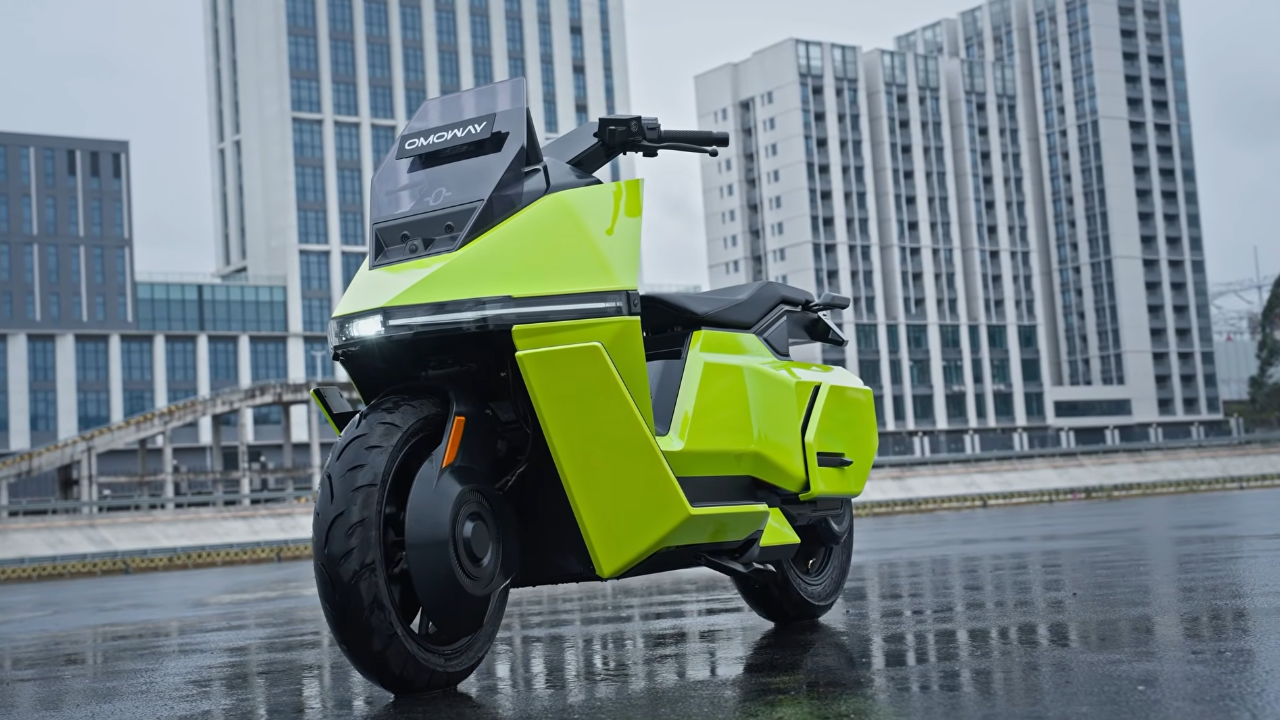 Neon yellow Omoway electric scooter on wet city pavement with tall buildings background.