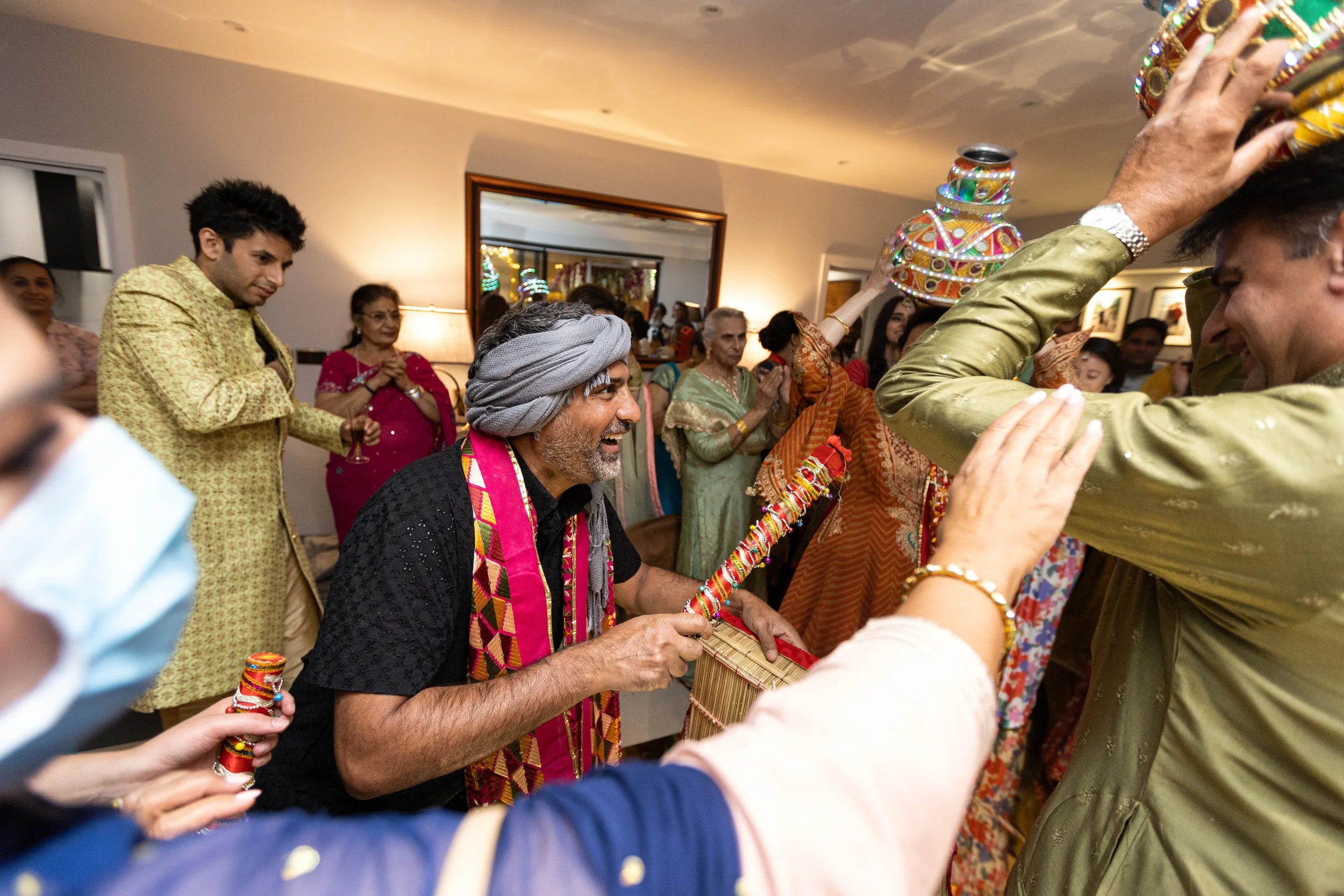 People celebrating an Indian wedding, dancing and playing musical instruments in a decorated indoor setting.