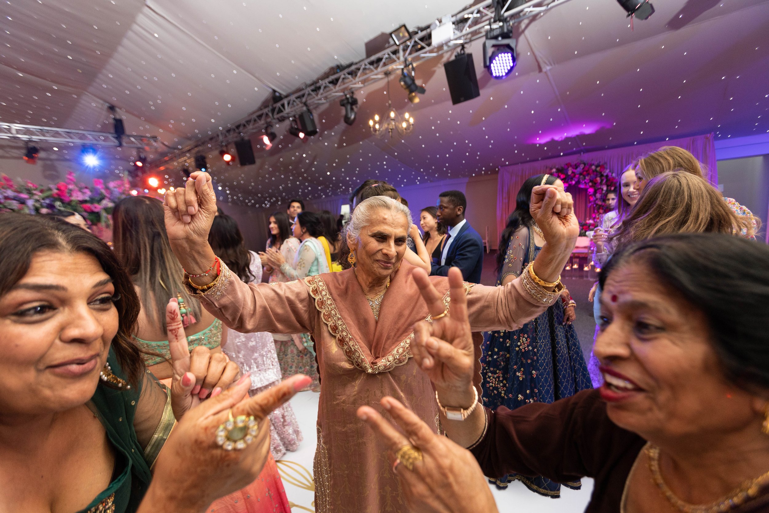 Women dancing and celebrating at a festive indoor event, with colorful attire and joyful expressions.