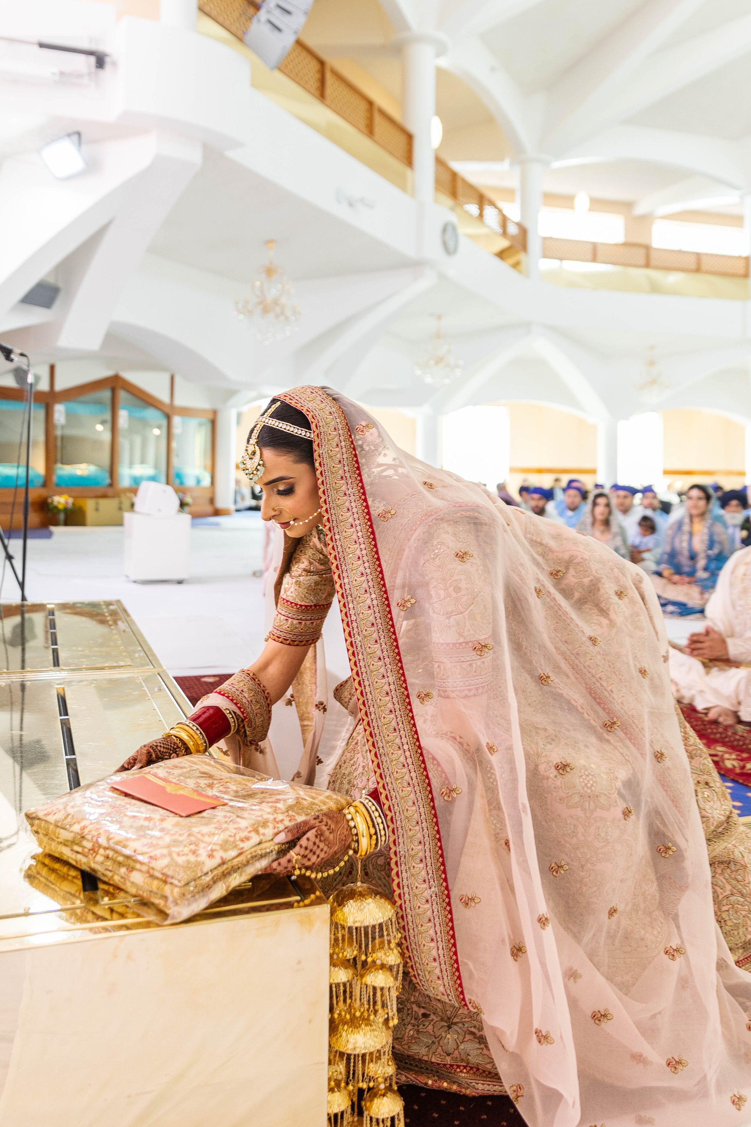 Indian bride in traditional attire at her wedding ceremony, bowing and performing a ritual.