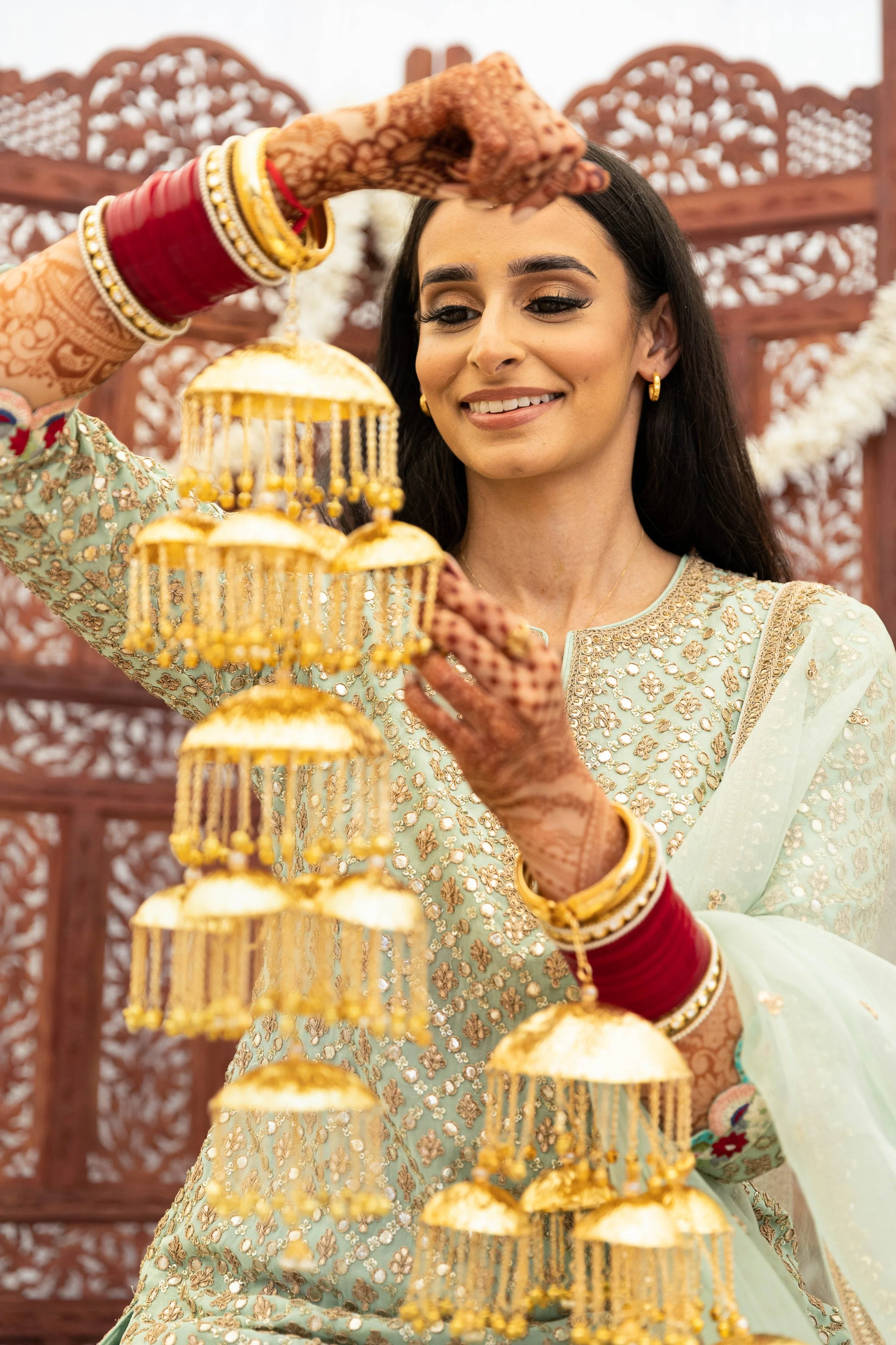 Woman in traditional Indian attire holding decorative hanging gold ornaments during celebration.
