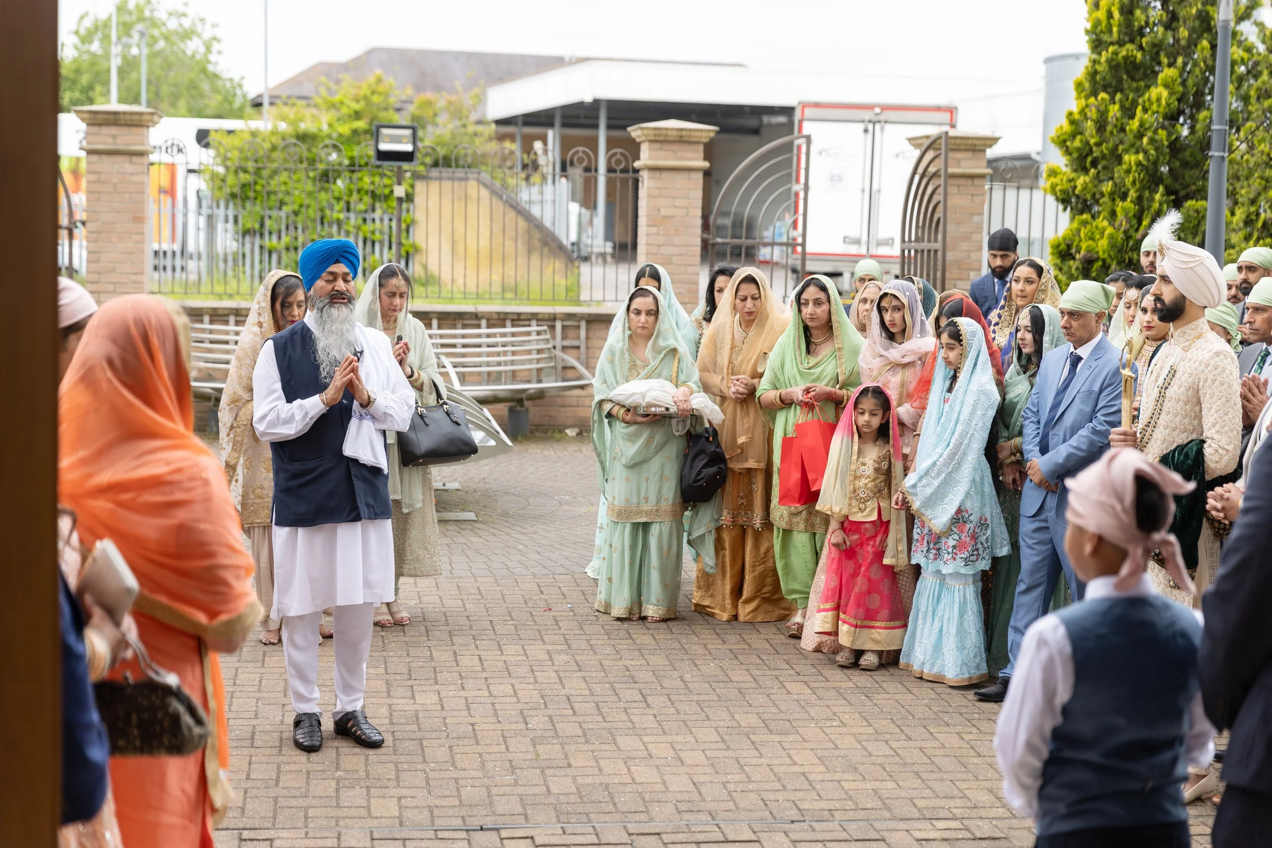 Hindu wedding ceremony with priest, bride, and groom surrounded by family and friends in colorful traditional attire outside.
