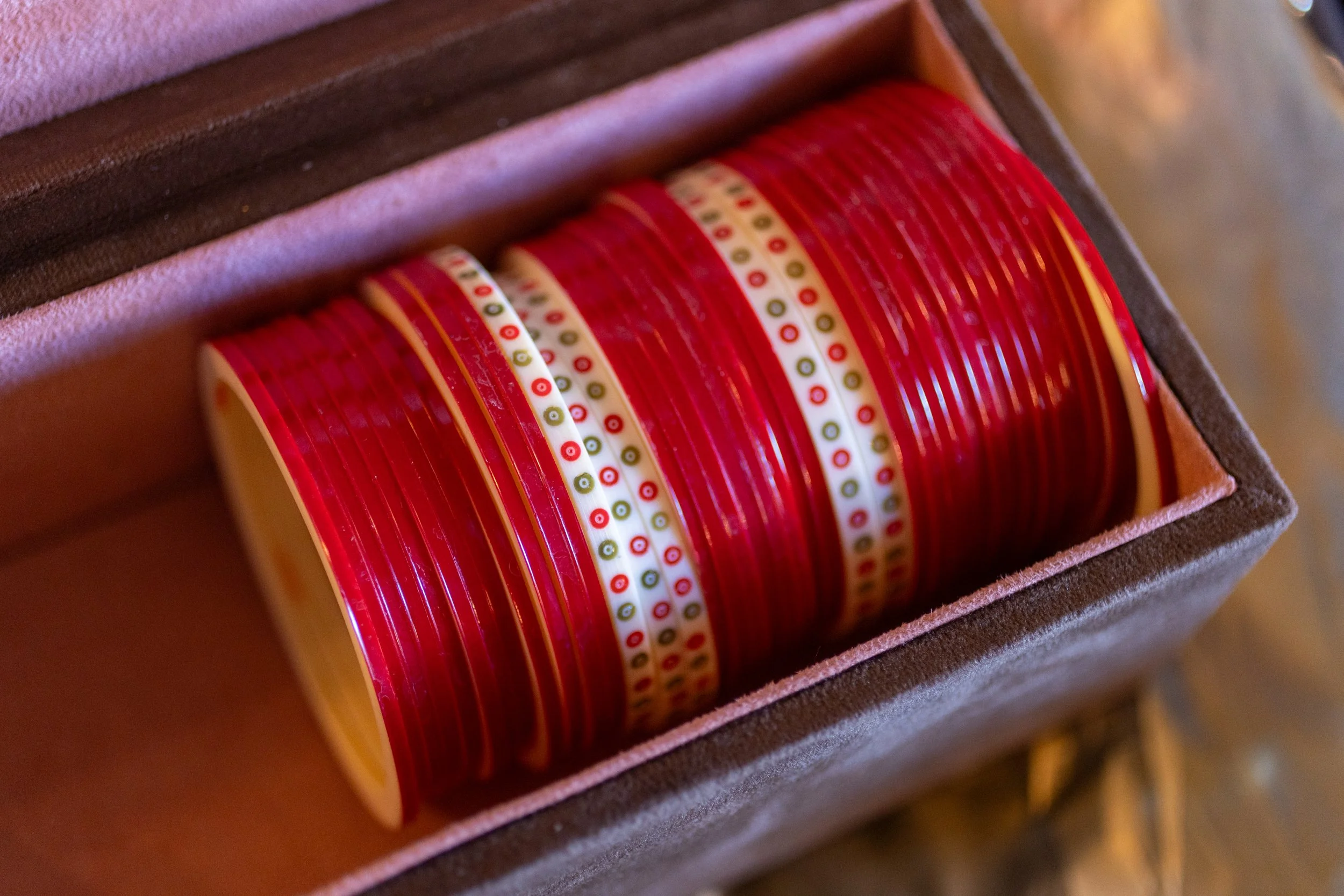 A box containing red and white bingo game markers, arranged neatly inside a velvet-lined container.