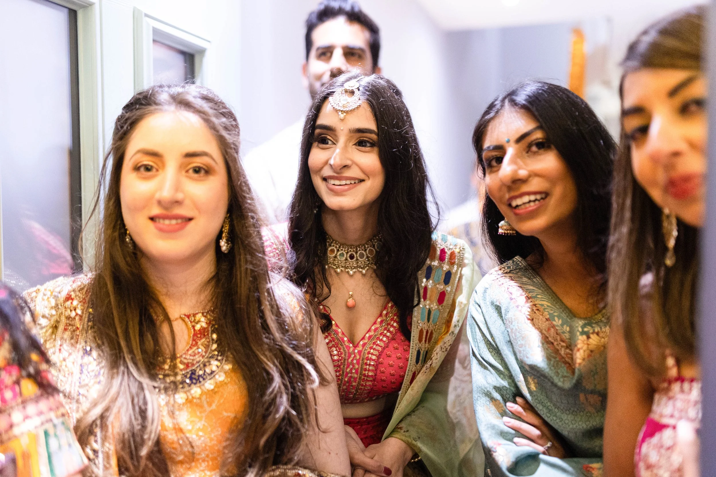 Group of women in colorful traditional Indian attire celebrating and smiling at a festive event.