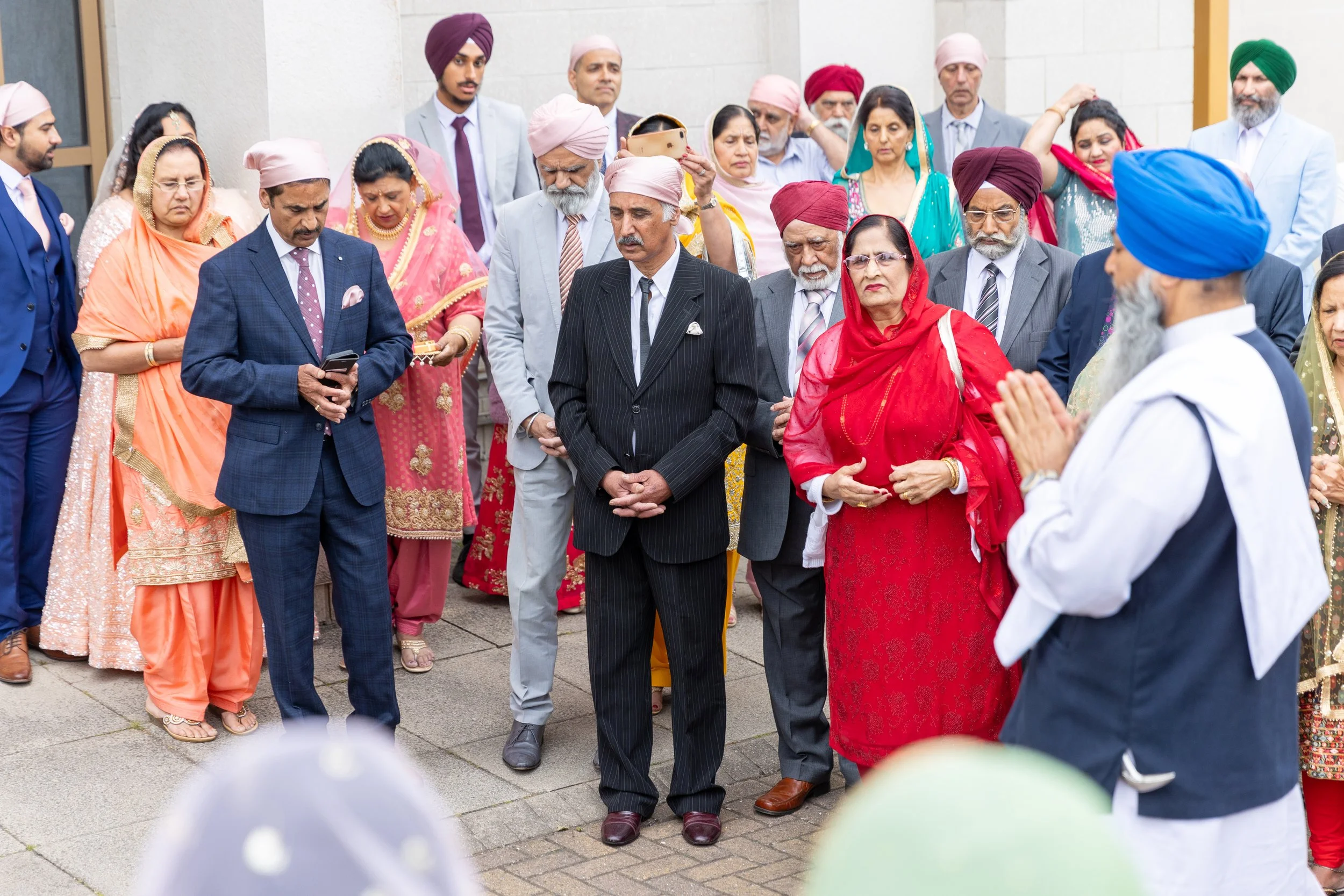 Group of Indian people praying outdoors, some with hands folded, attending a religious or cultural event