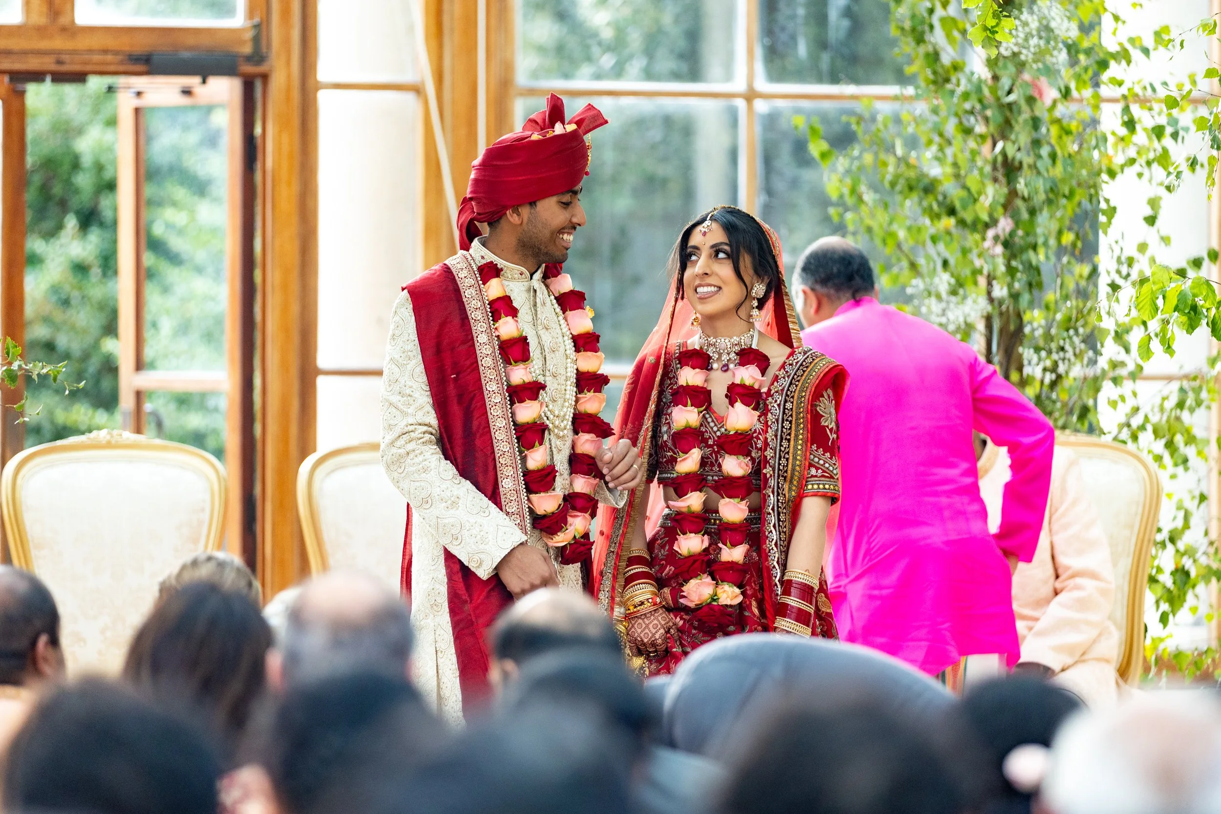 Indian bride and groom dressed in traditional wedding attire during their wedding ceremony, surrounded by family and guests.