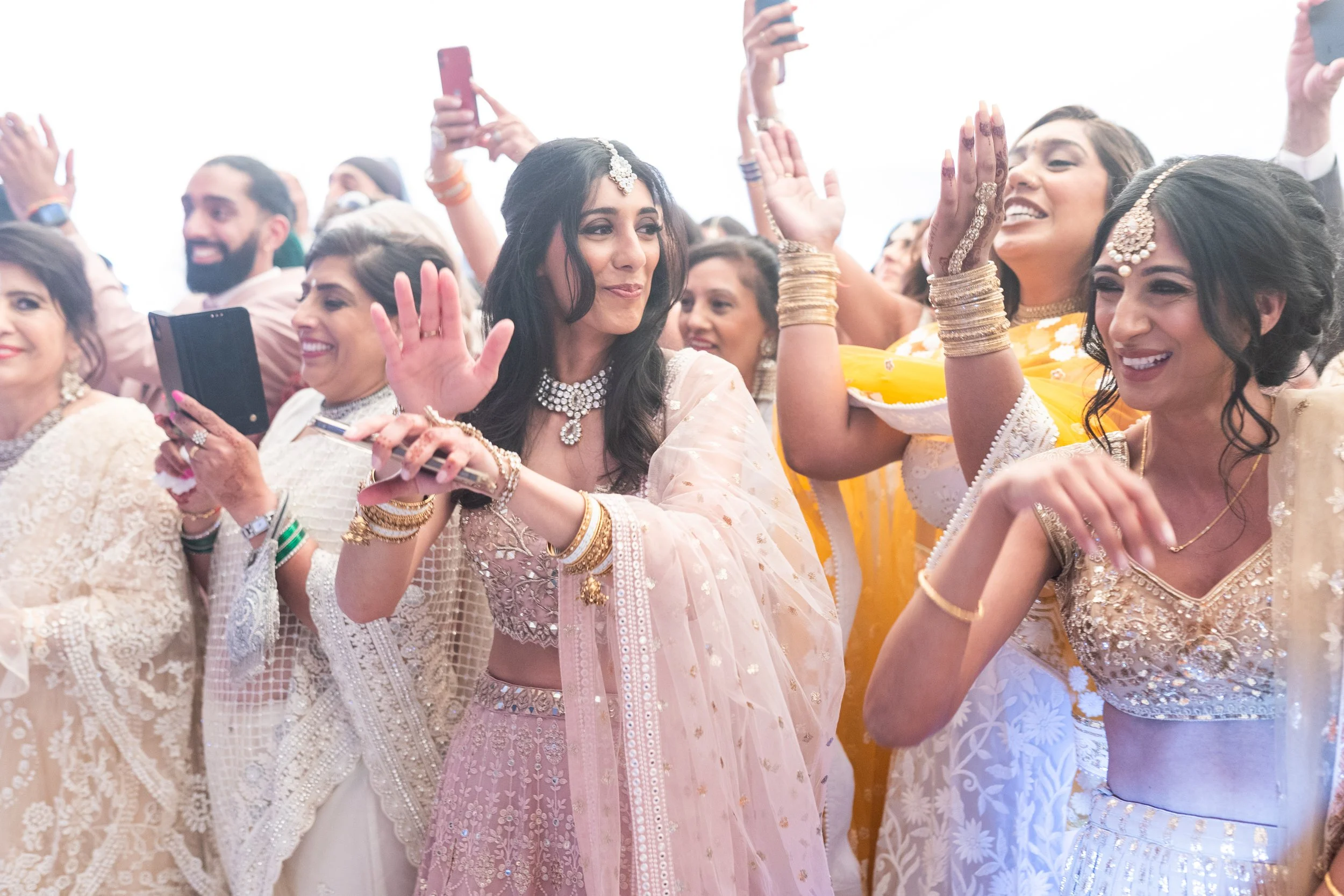 Group of women in traditional Indian attire celebrating and dancing at a festive event