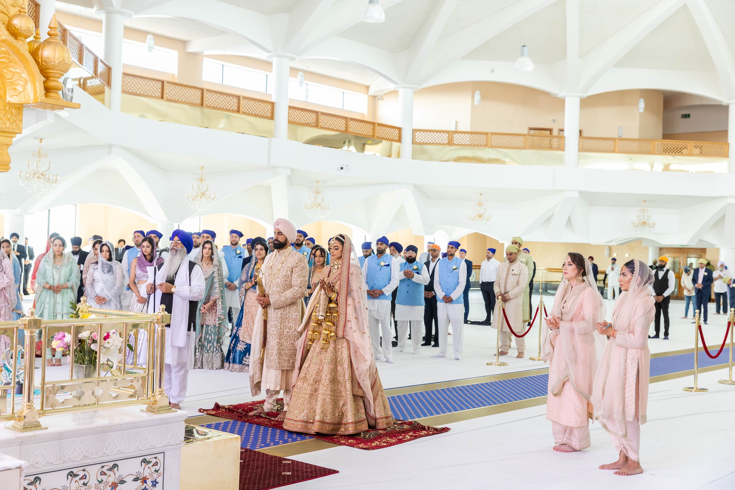Indian wedding ceremony with bride and groom in traditional attire, surrounded by family members in ceremonial setting.