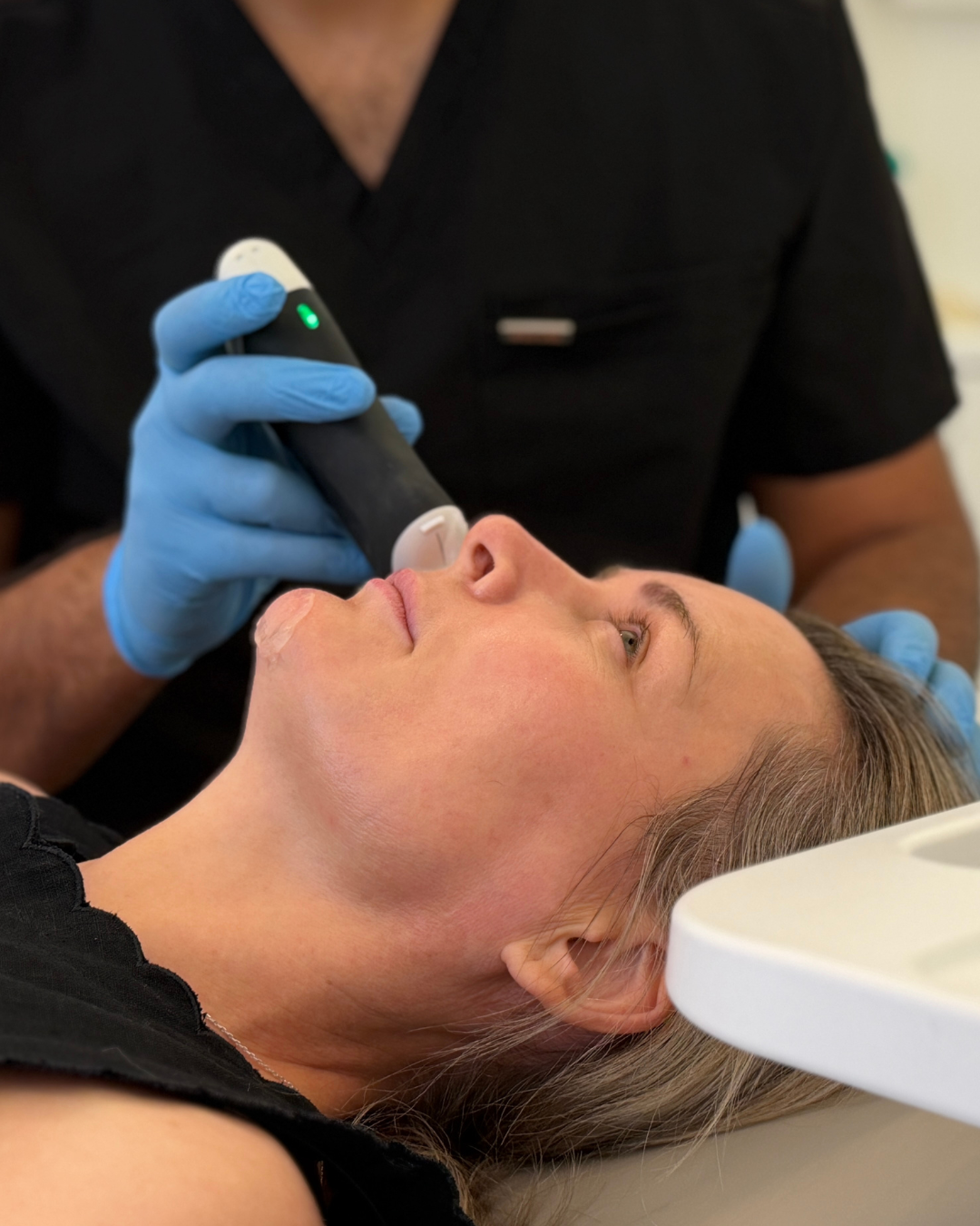Dr Karwal performing a ultrasound examination on a patient's face at Karwal Aesthetics in Mayfair, London.
