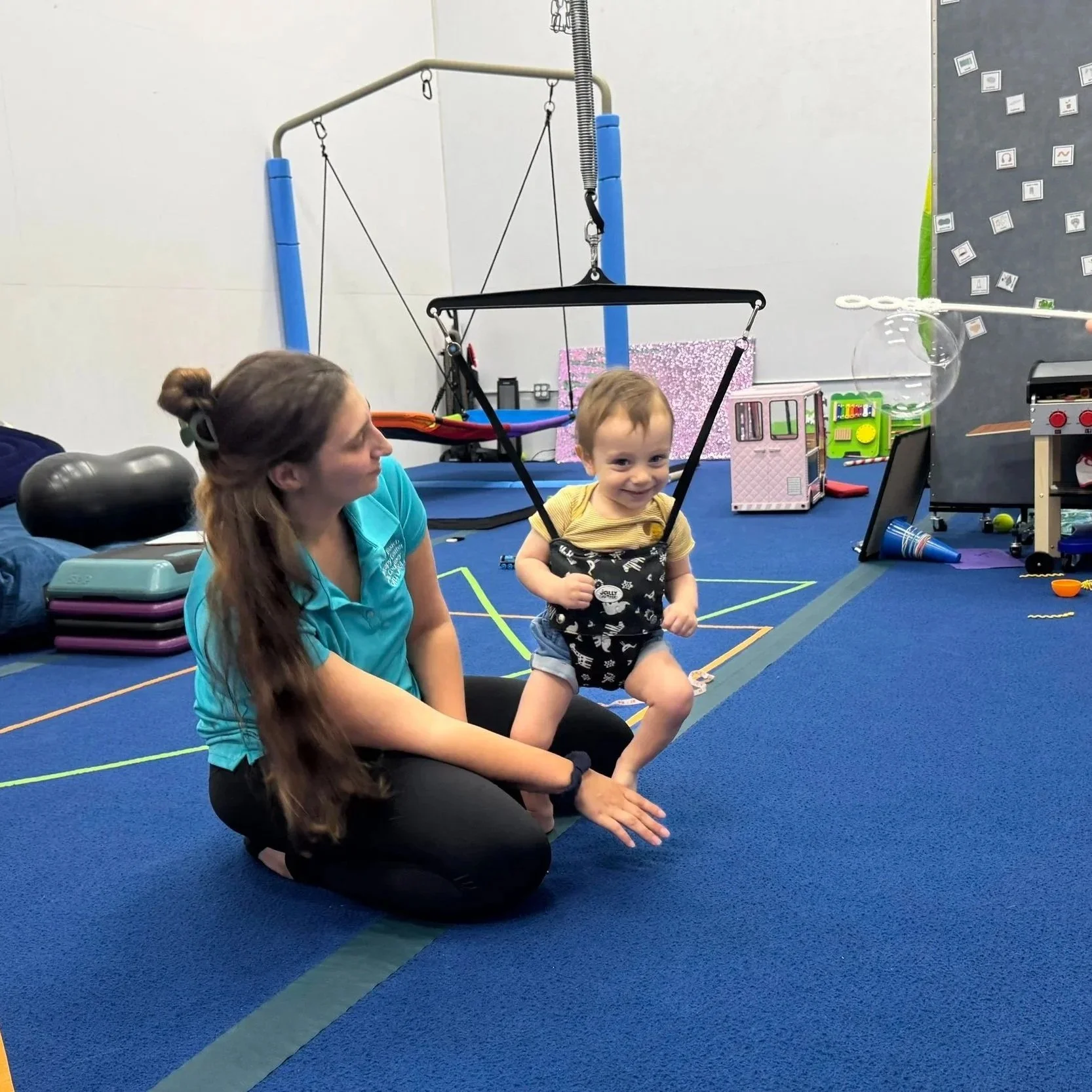 Infant using a baby zipline support system with an occupational therapist to address delayed walking milestones at Apollo Beach Therapy Center.