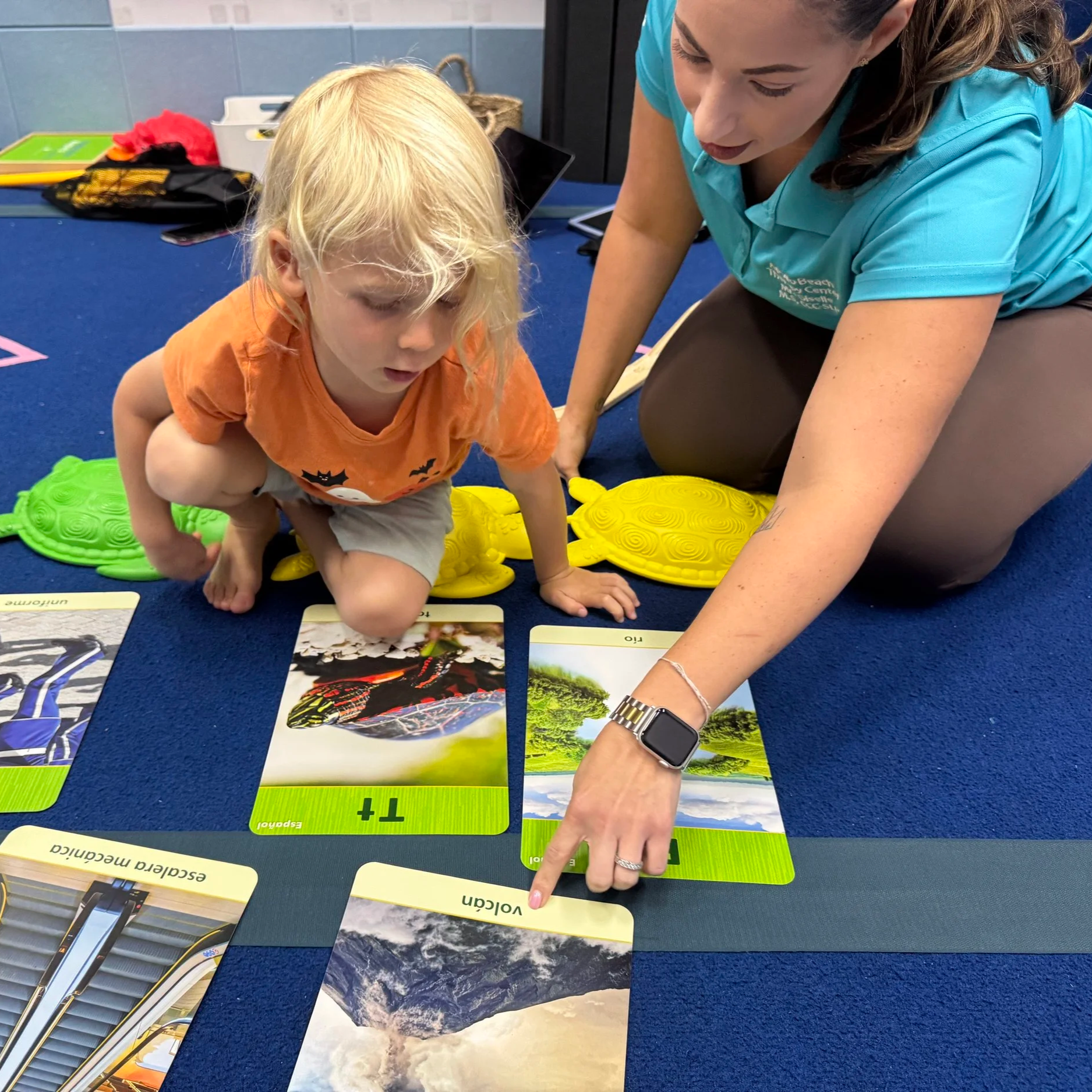 Therapist supporting a child with picture-based communication and learning activities during pediatric therapy at Apollo Beach Therapy Center.