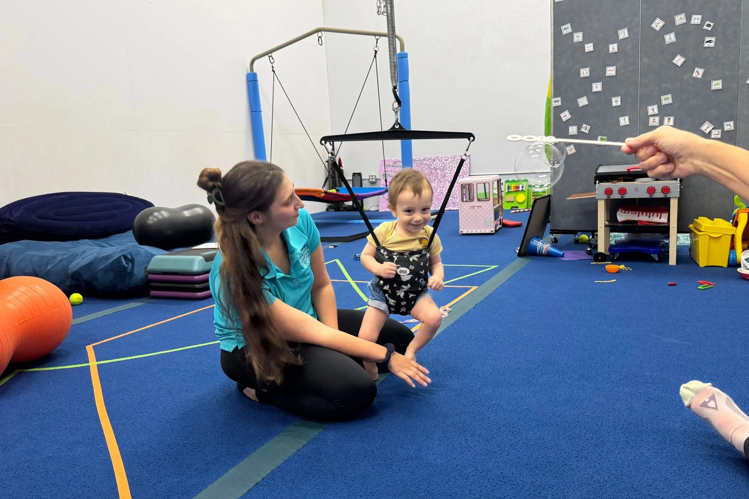 Infant using a baby zipline support system with an occupational therapist to address delayed walking milestones at Apollo Beach Therapy Center.