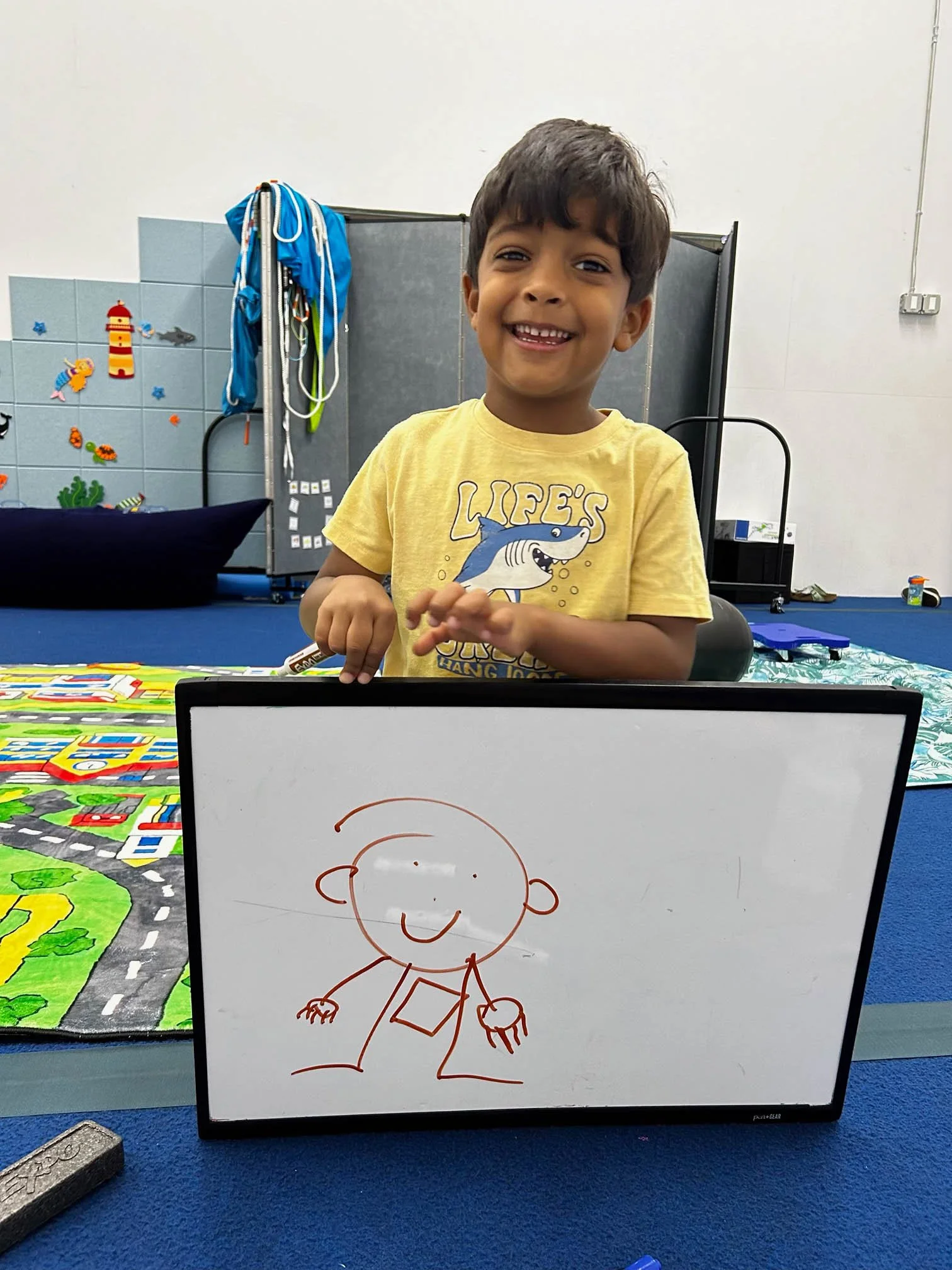 Child displaying a drawing during a fine motor and visual-motor occupational therapy activity at Apollo Beach Therapy Center.