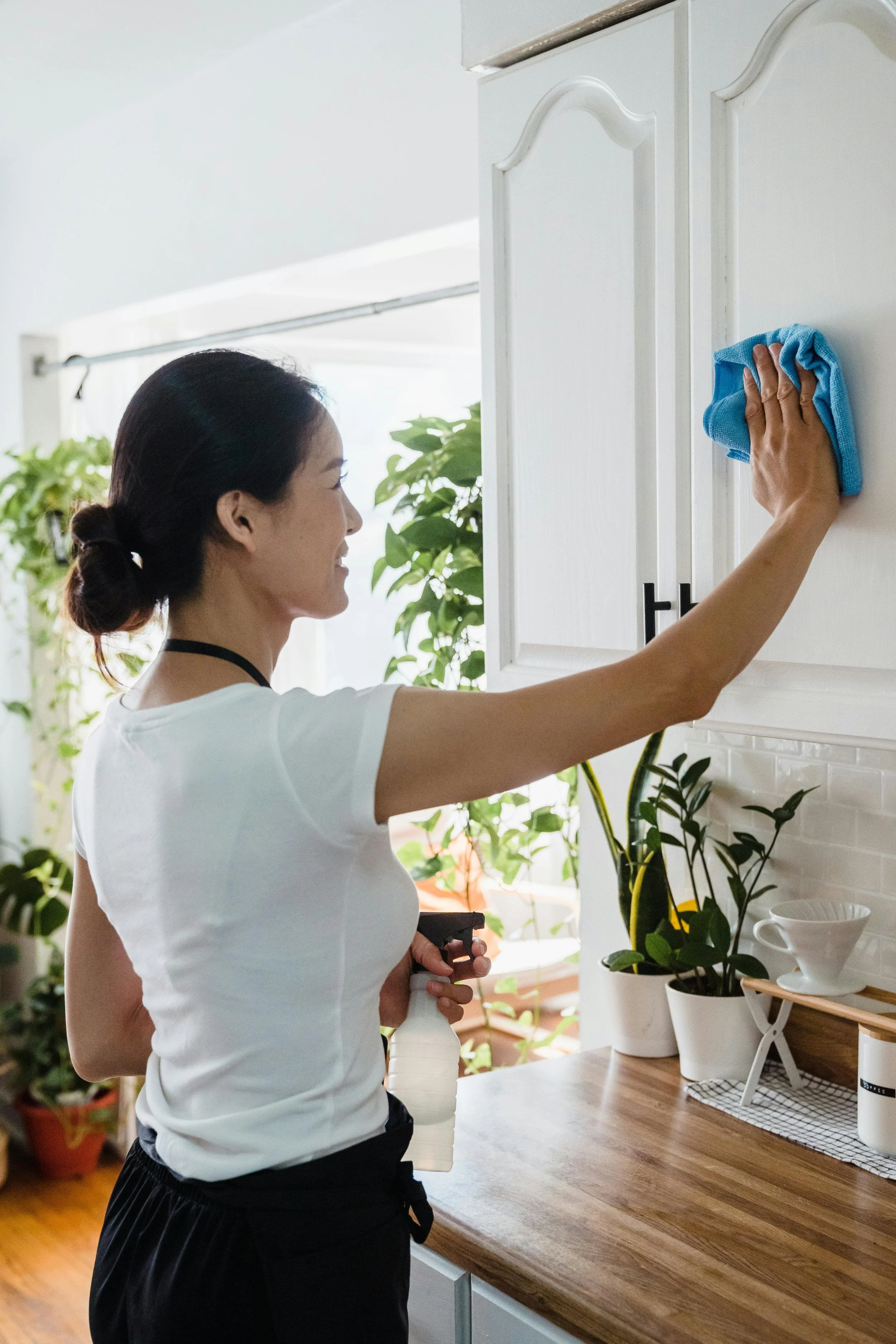 A woman wiping down her kitchen cabinets