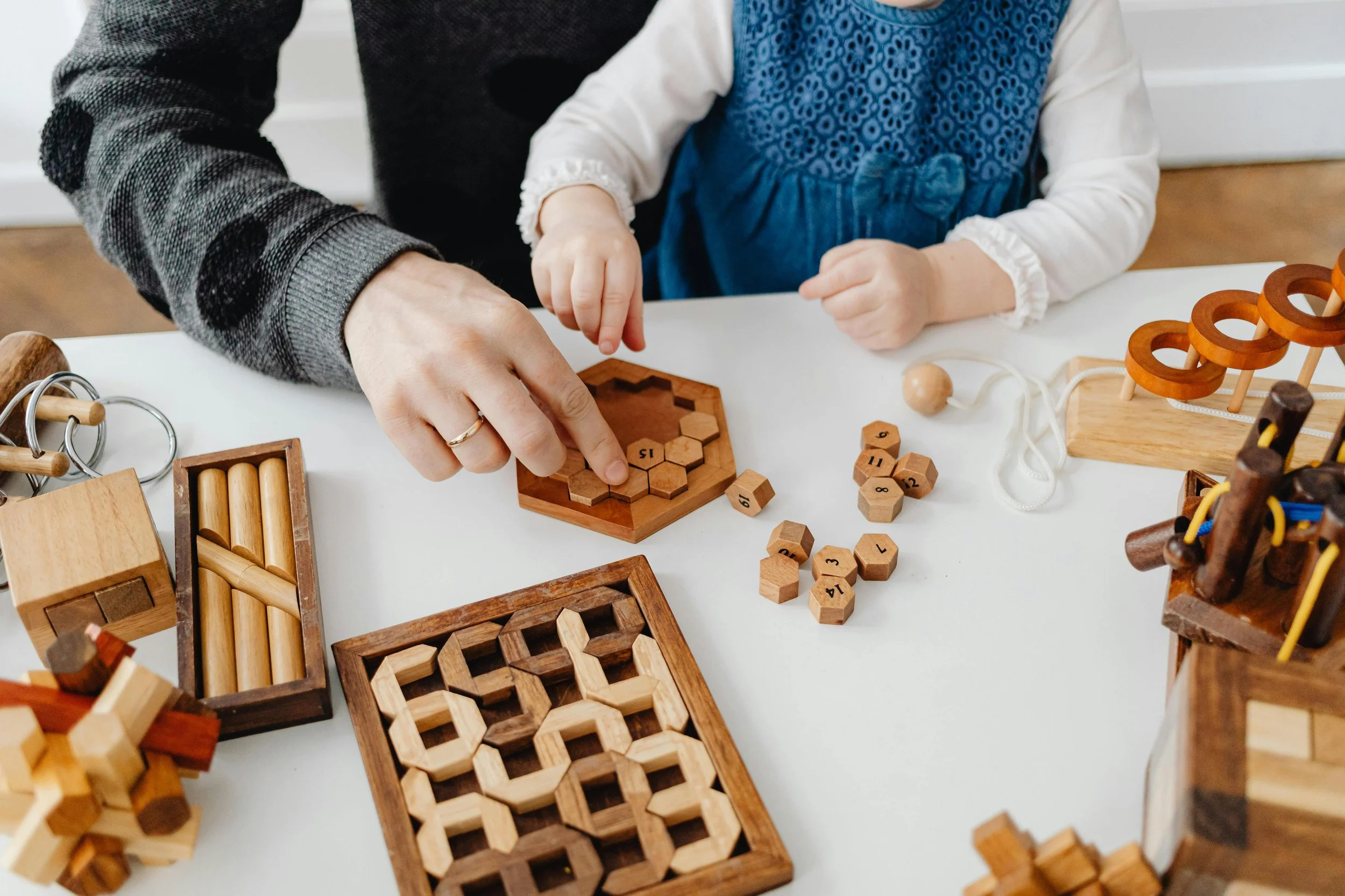 A kid and their parent playing with wooden toys together