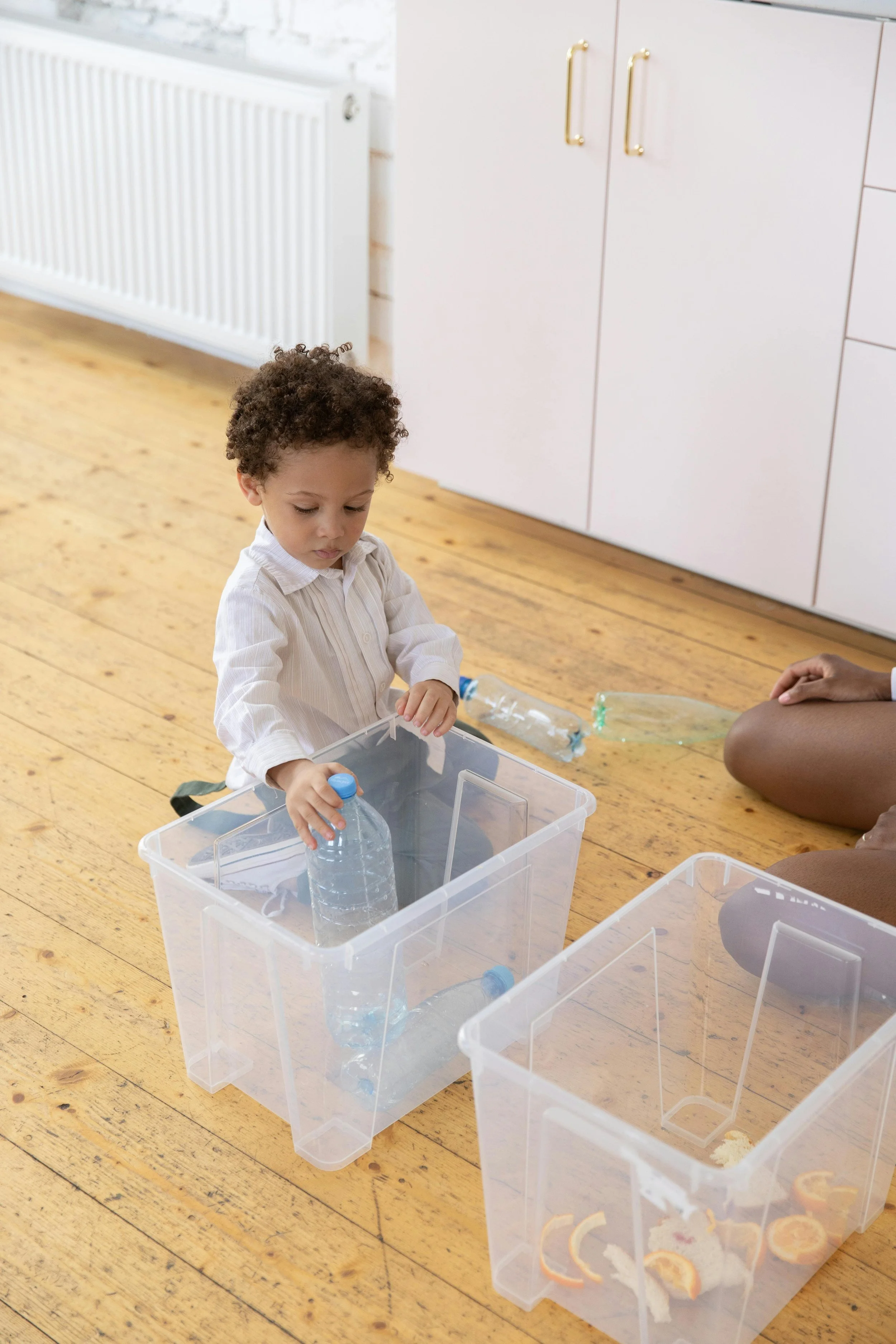 A young boy separating plastic water bottles and orange peels