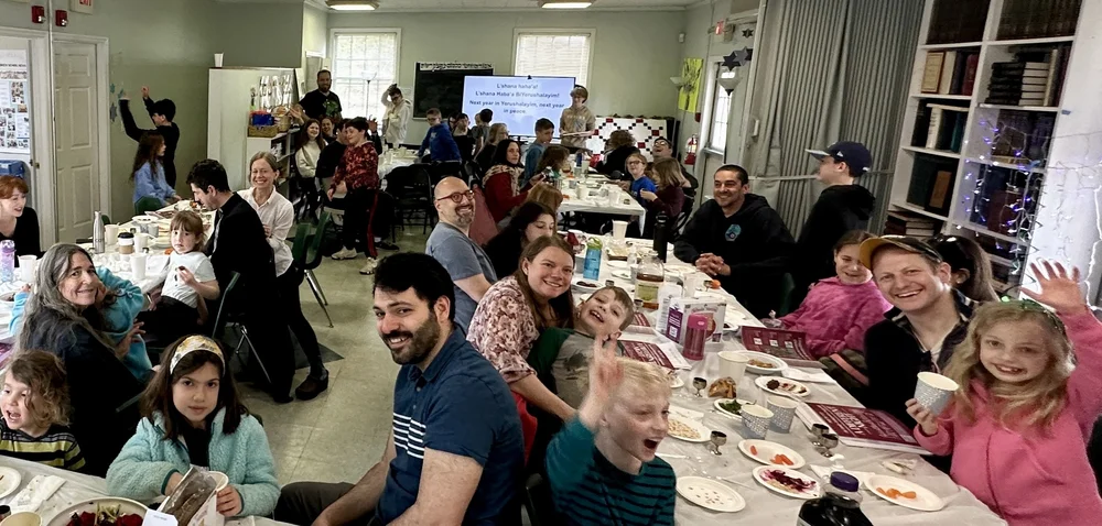 A long table of families of all ages together at a model seder.