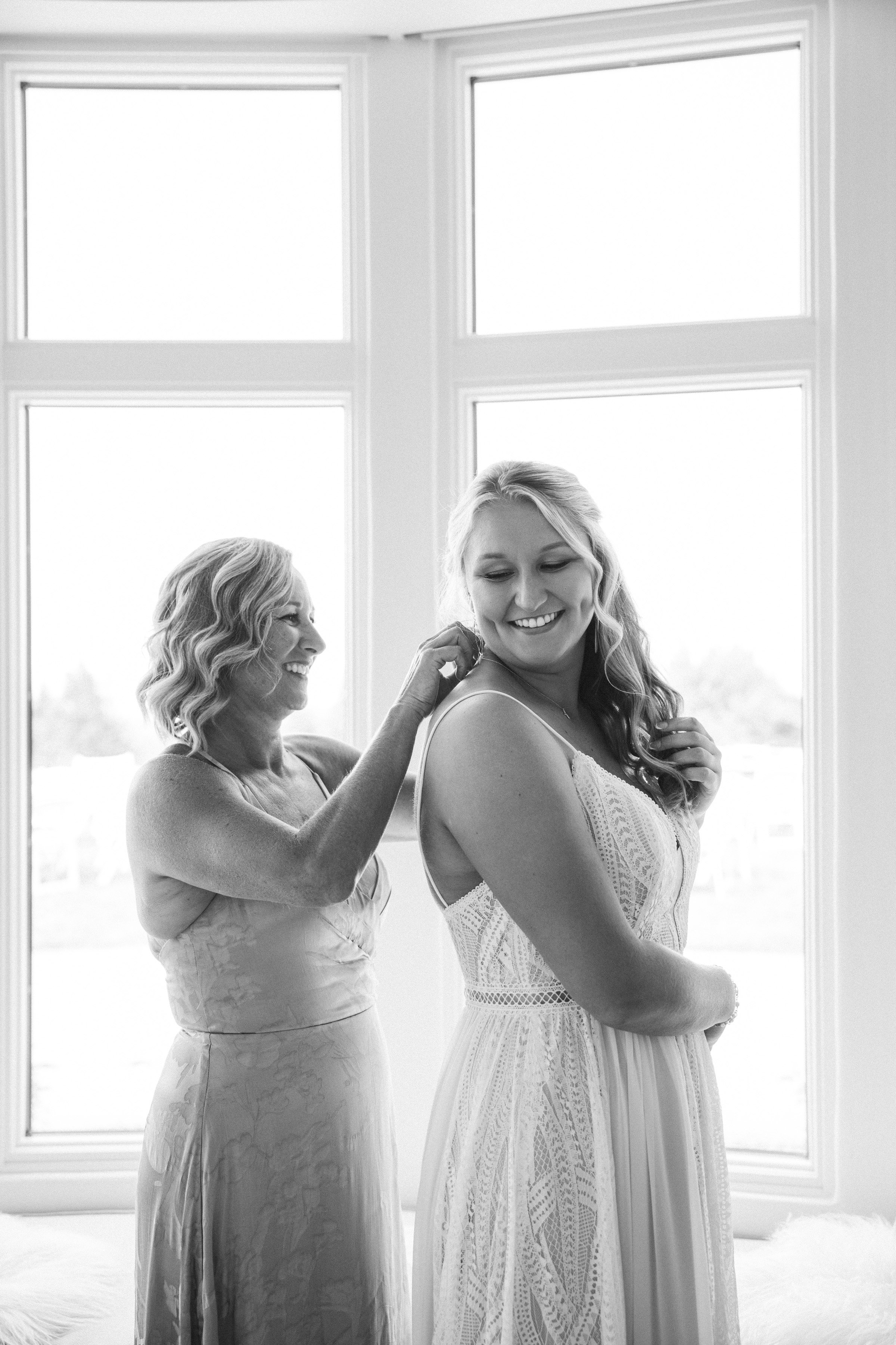 Black and white photo bride getting ready with mom in window light