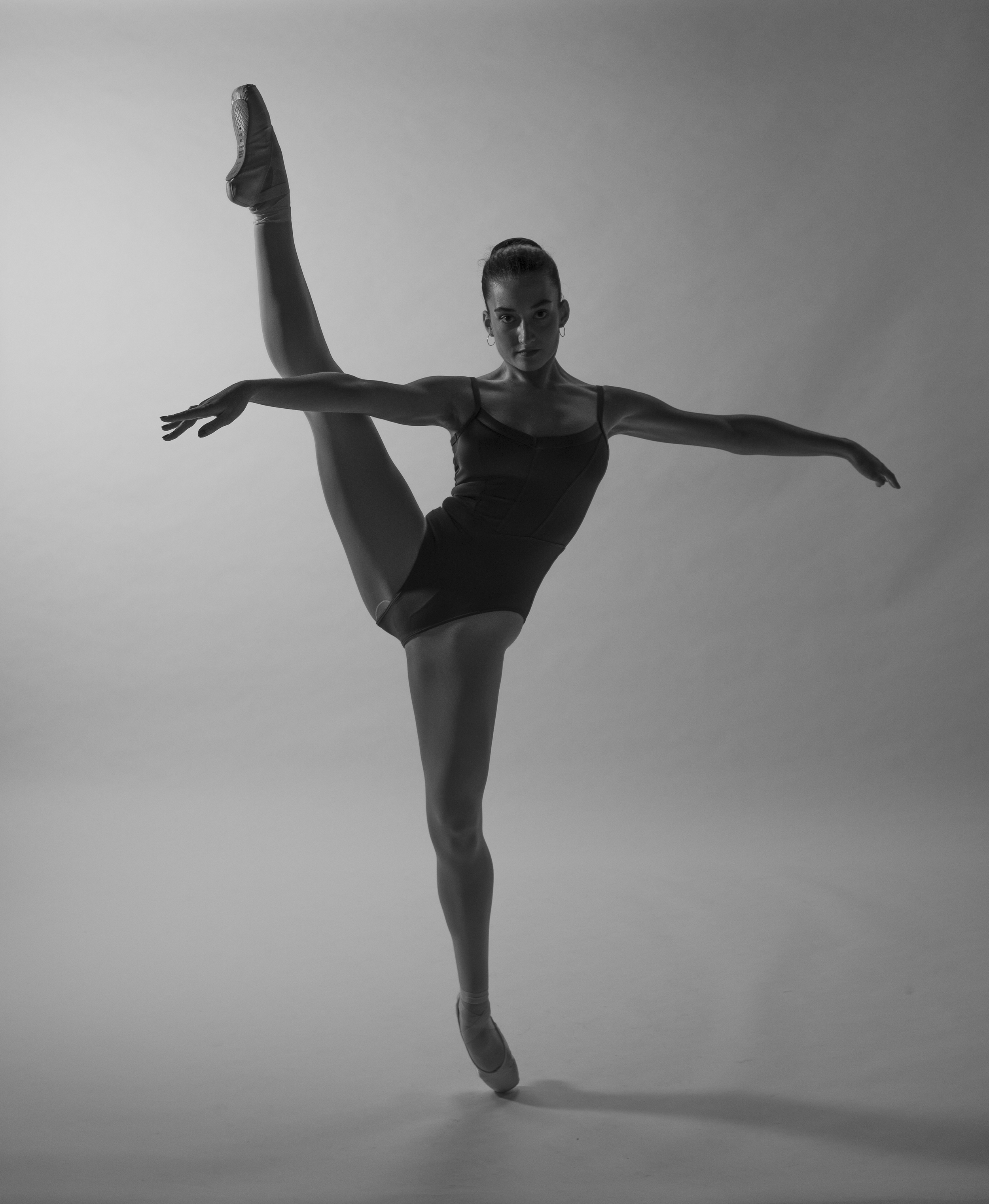 Black and white photo of a female ballet dancer performing a pose in a studio.