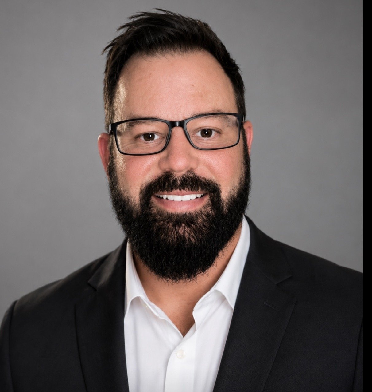 Man with glasses and a beard wearing a suit and tie
