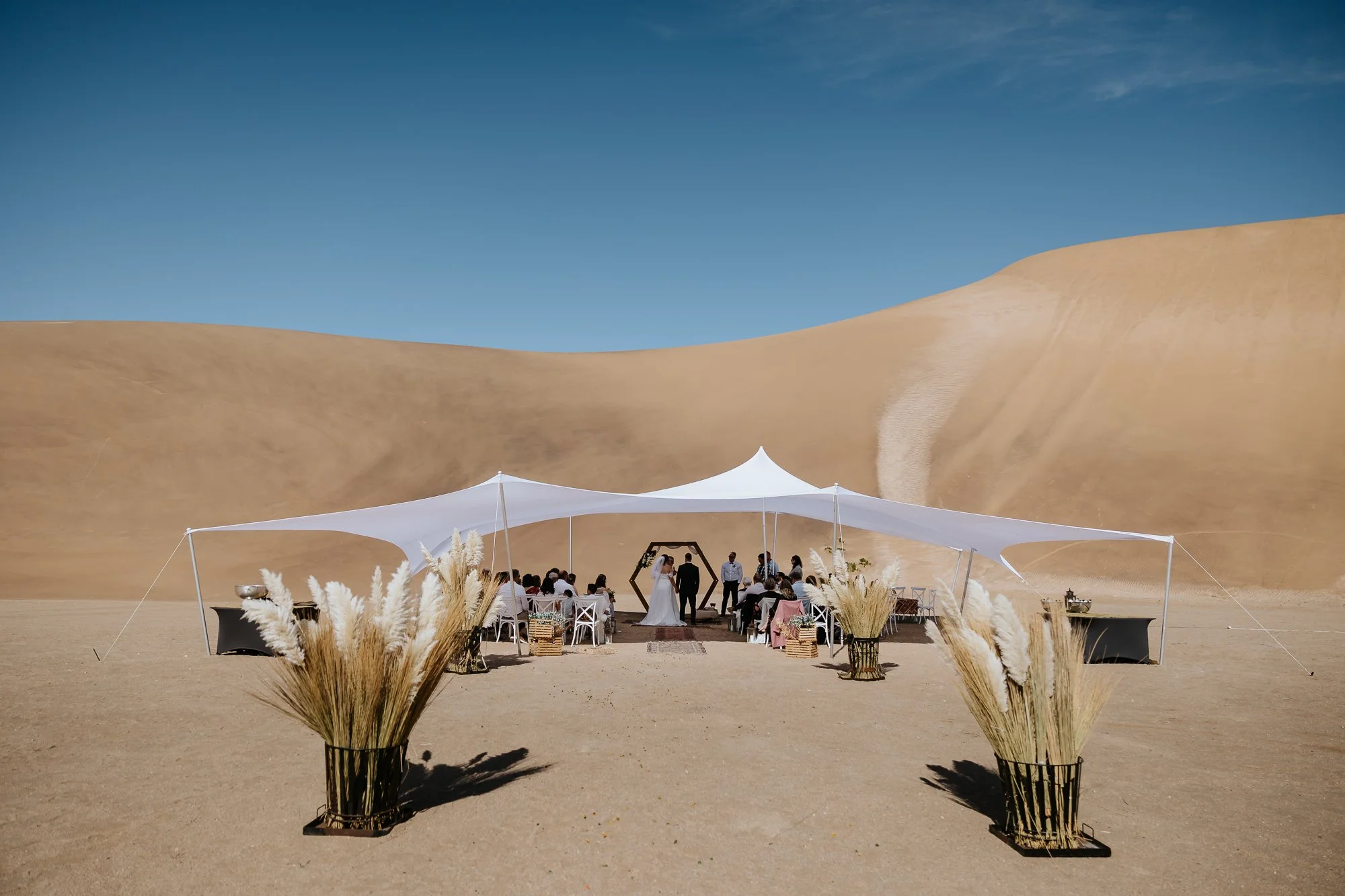 Wedding ceremony beneath a stretch tent surrounded by Namibian dunes