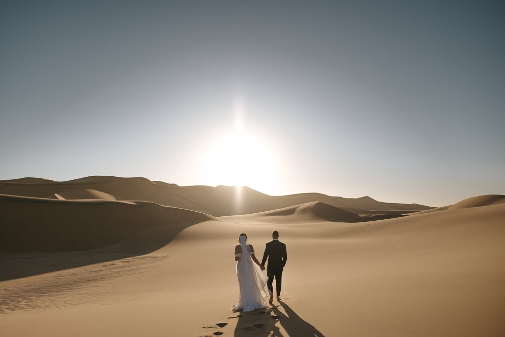 Bride and groom walking in the Namibian desert on their wedding day