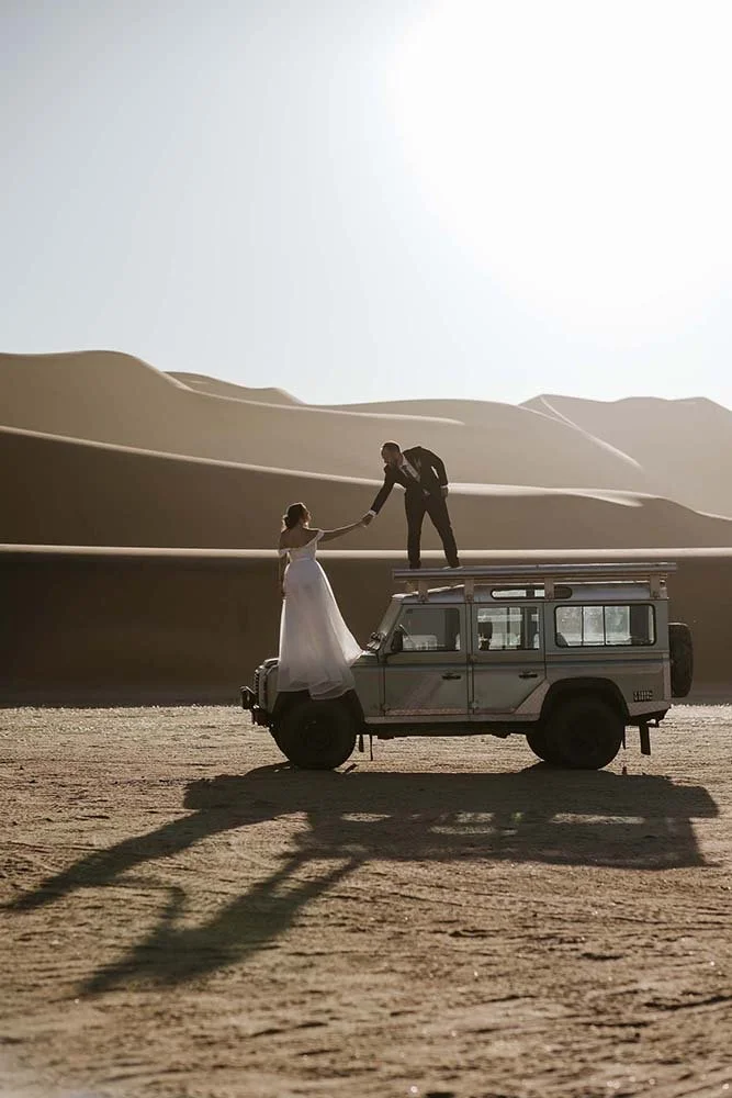 Groom helping his bride on an old Land Rover in the Namibian desert outside Swakopmund 