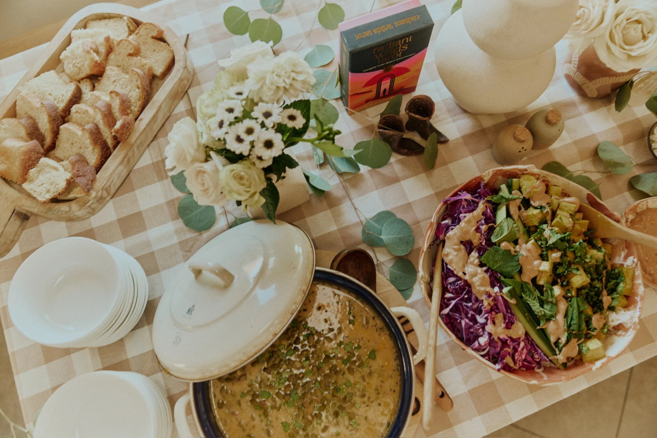Table with assorted food items including bread, salad, soup, and decorative flowers.