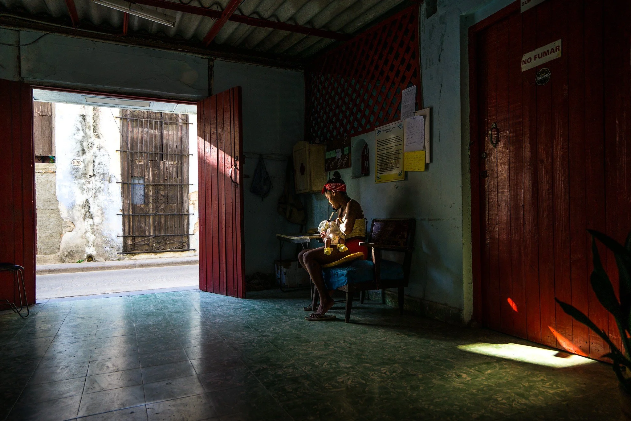A woman sits with her child in the entrance of the boxing gym © Chantale Wong
