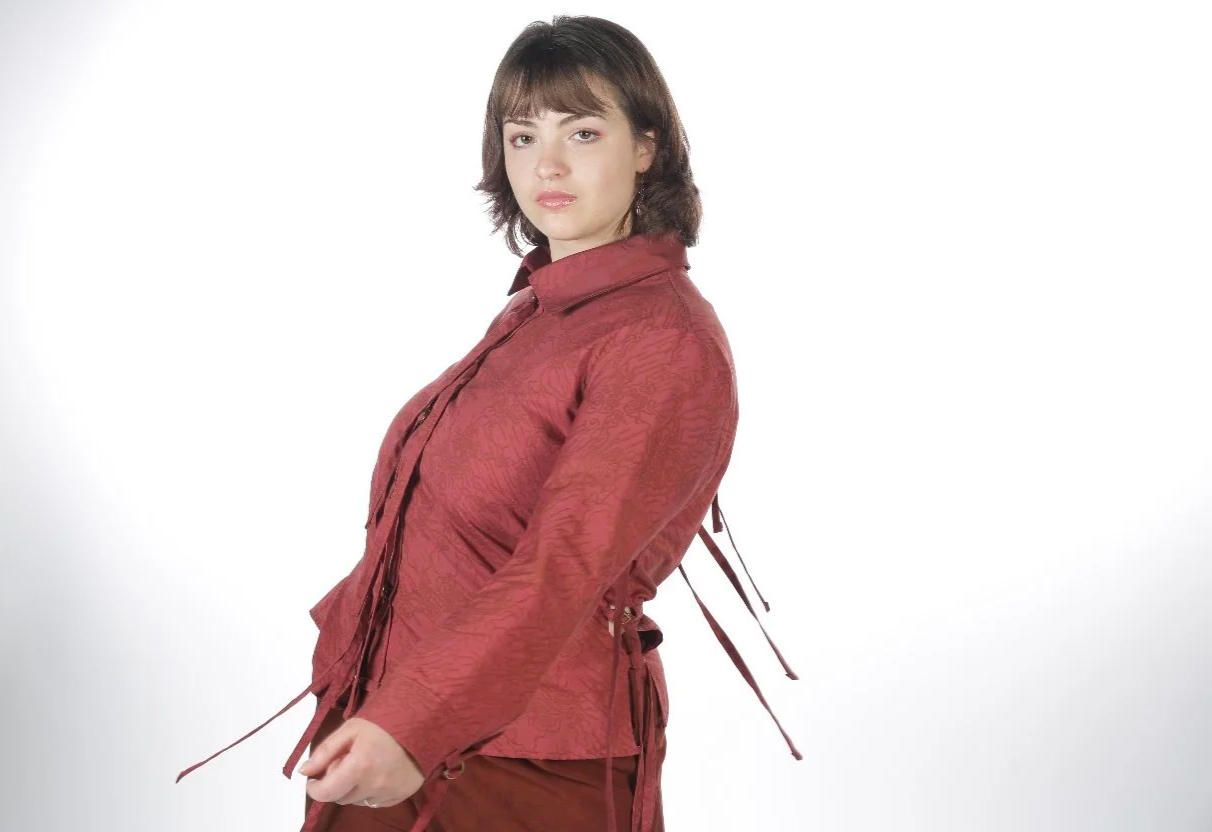 Young woman wearing a red jacket standing against a white background.